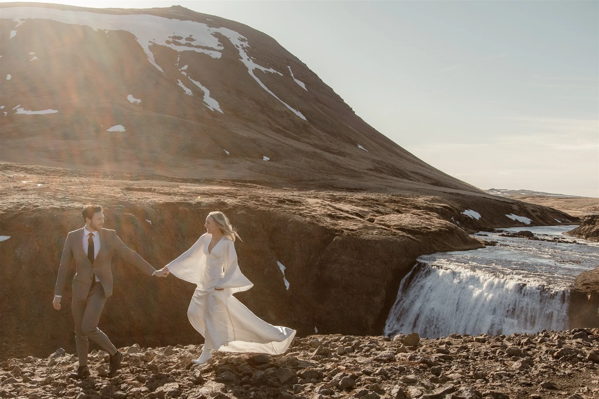 Lord of the Rings Inspired Iceland Engagement Photoshoot at waterfall — couple walking with Arwen inspired dress