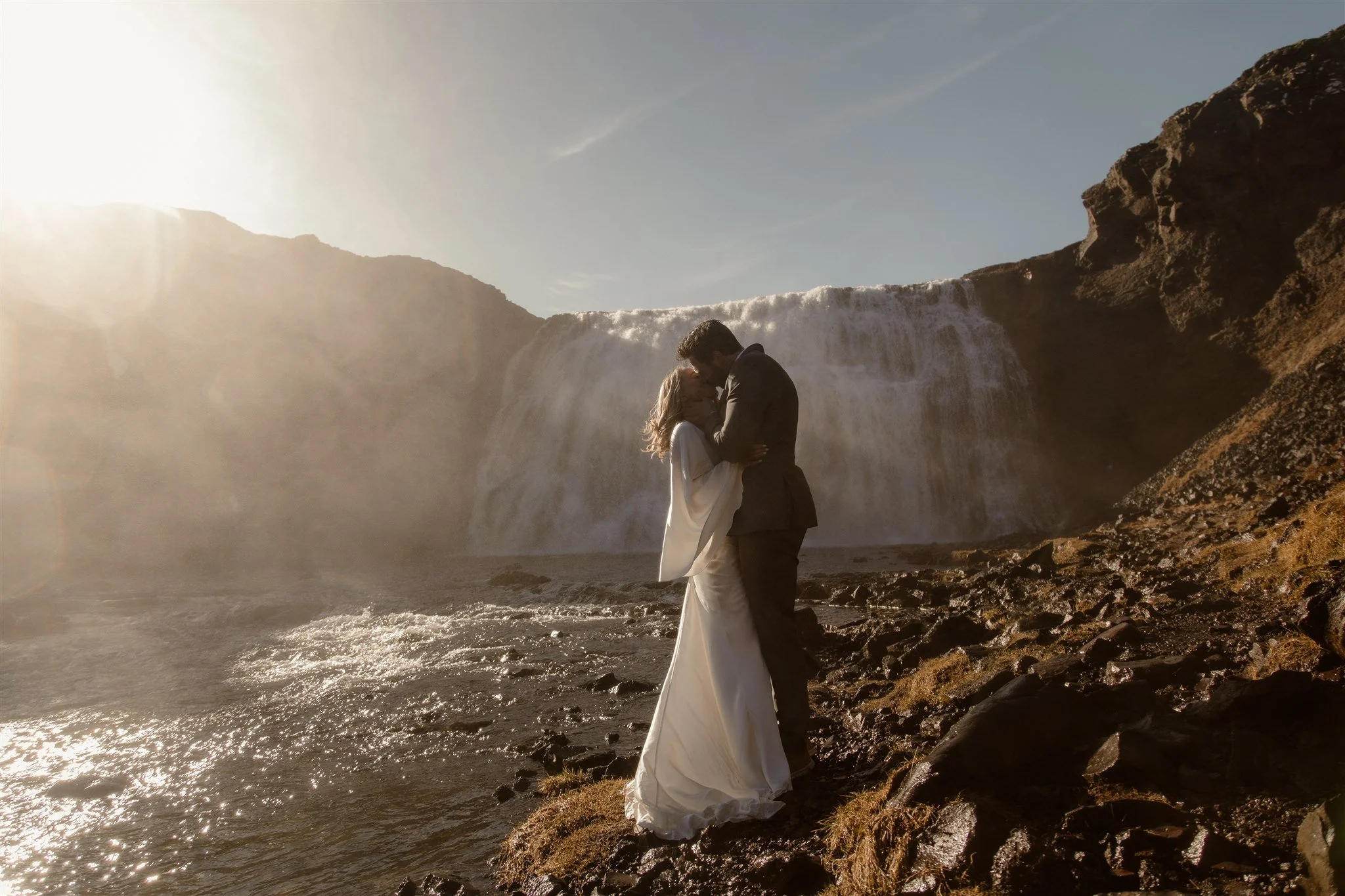 Lord of the Rings Inspired Iceland Engagement Photoshoot at waterfall — couple standing together with Arwen inspired dress with beautiful light and waterfall mist