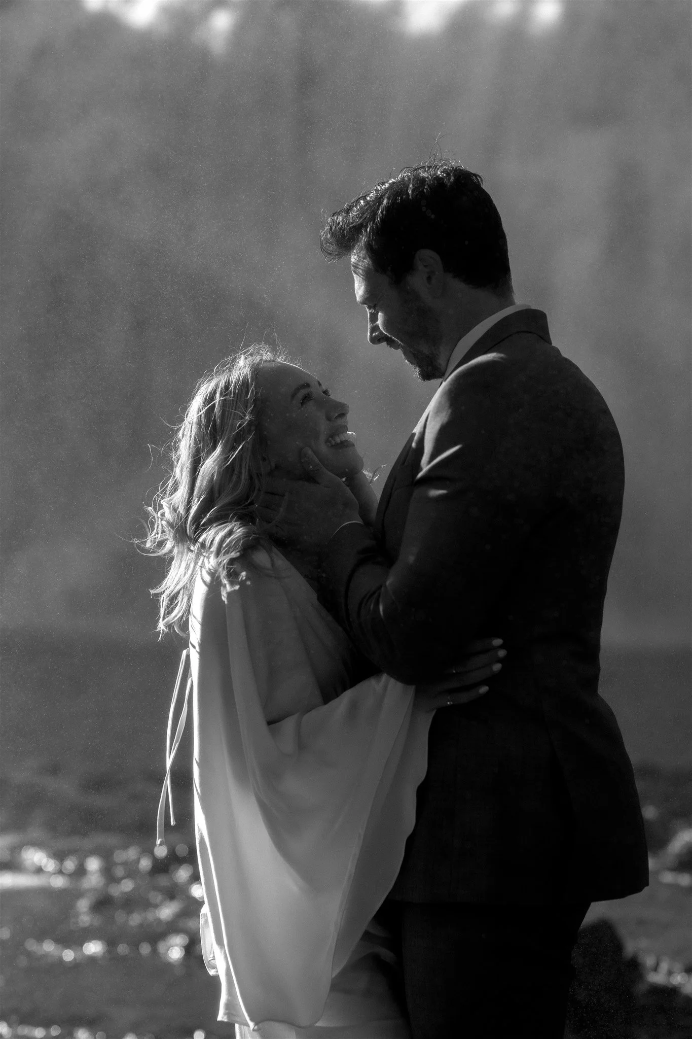 Lord of the Rings Inspired Iceland Engagement Photoshoot at waterfall — couple standing together with Arwen inspired dress with beautiful light and waterfall mist