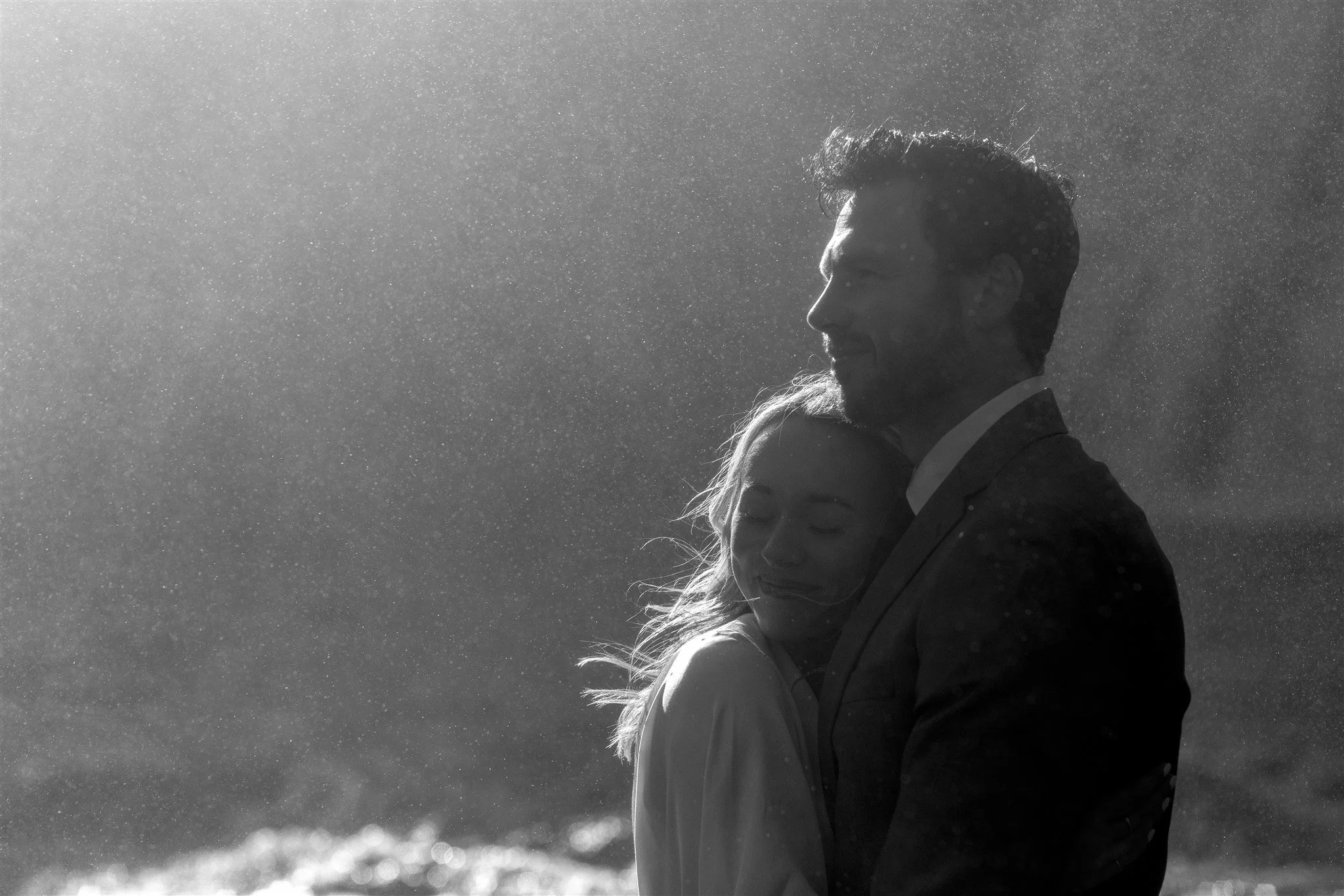 Lord of the Rings Inspired Iceland Engagement Photoshoot at waterfall — couple standing together with Arwen inspired dress with beautiful light and waterfall mist