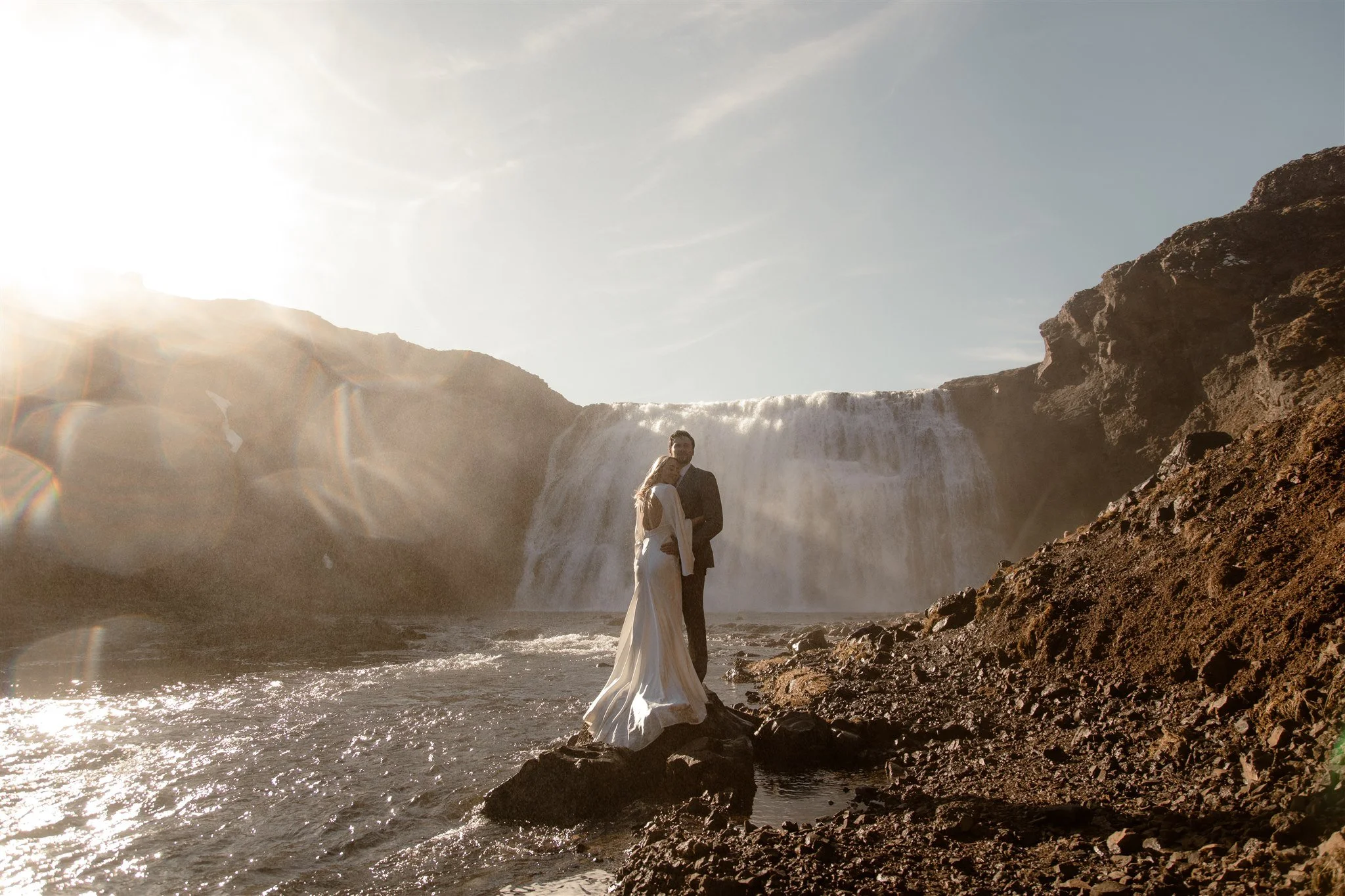 Lord of the Rings Inspired Iceland Engagement Photoshoot at waterfall — couple standing together with Arwen inspired dress with beautiful light and waterfall mist