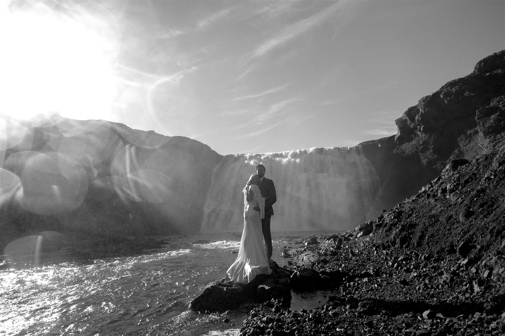 Lord of the Rings Inspired Iceland Engagement Photoshoot at waterfall — couple standing together with Arwen inspired dress with beautiful light and waterfall mist