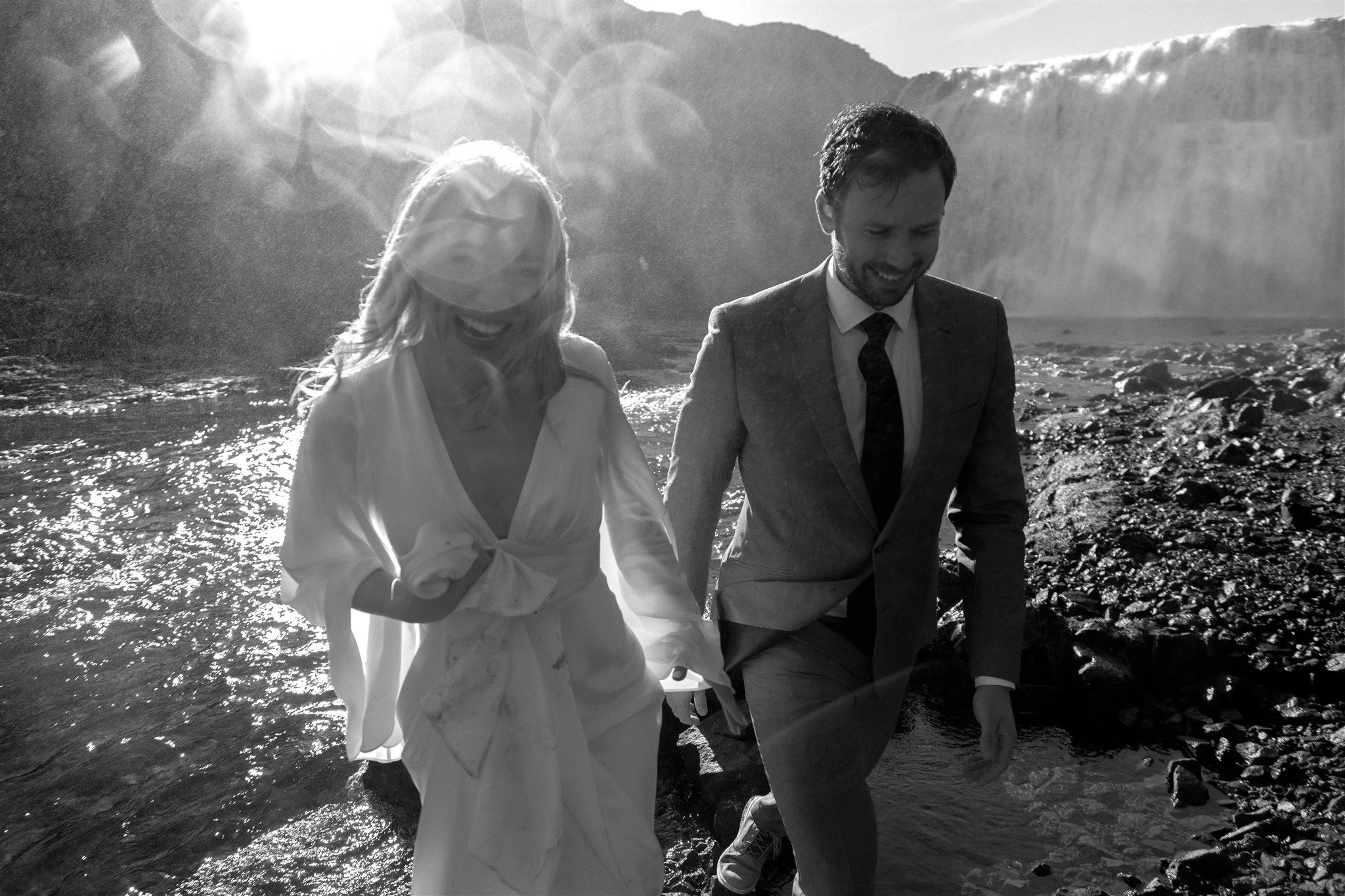 Lord of the Rings Inspired Iceland Engagement Photoshoot at waterfall — couple standing together with Arwen inspired dress with beautiful light and waterfall mist
