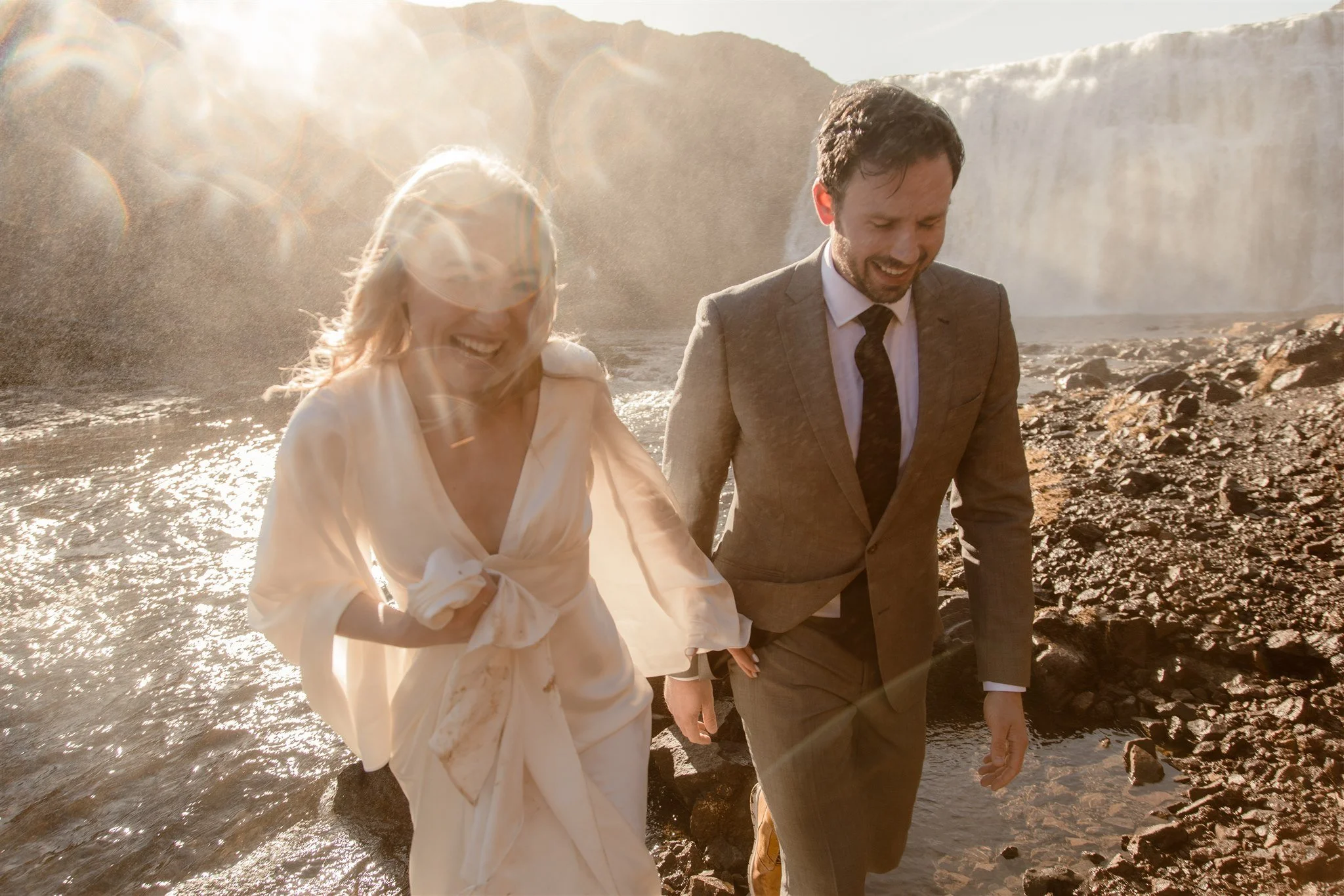 Lord of the Rings Inspired Iceland Engagement Photoshoot at waterfall — couple standing together with Arwen inspired dress with beautiful light and waterfall mist