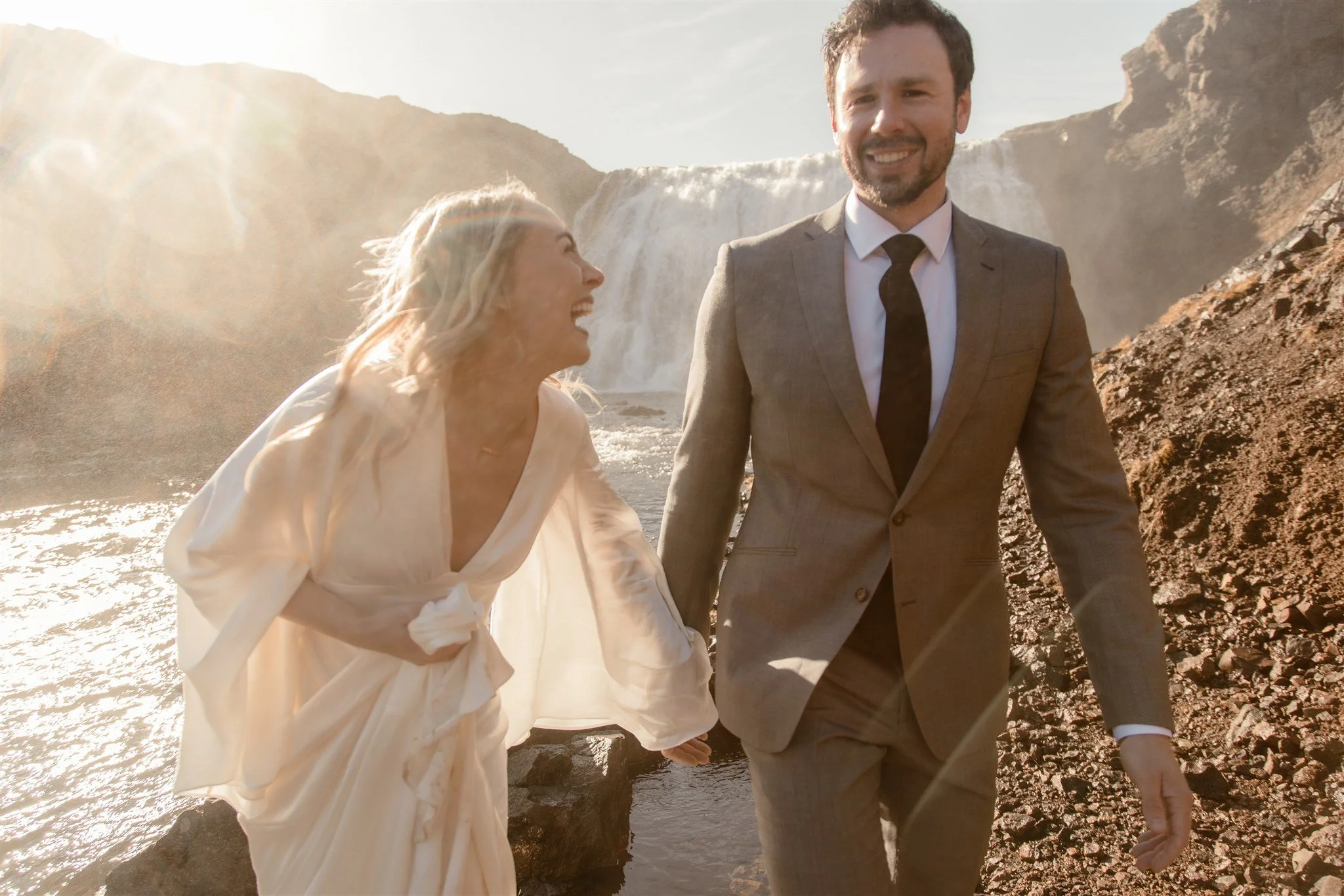 Lord of the Rings Inspired Iceland Engagement Photoshoot at waterfall — couple standing together with Arwen inspired dress with beautiful light and waterfall mist