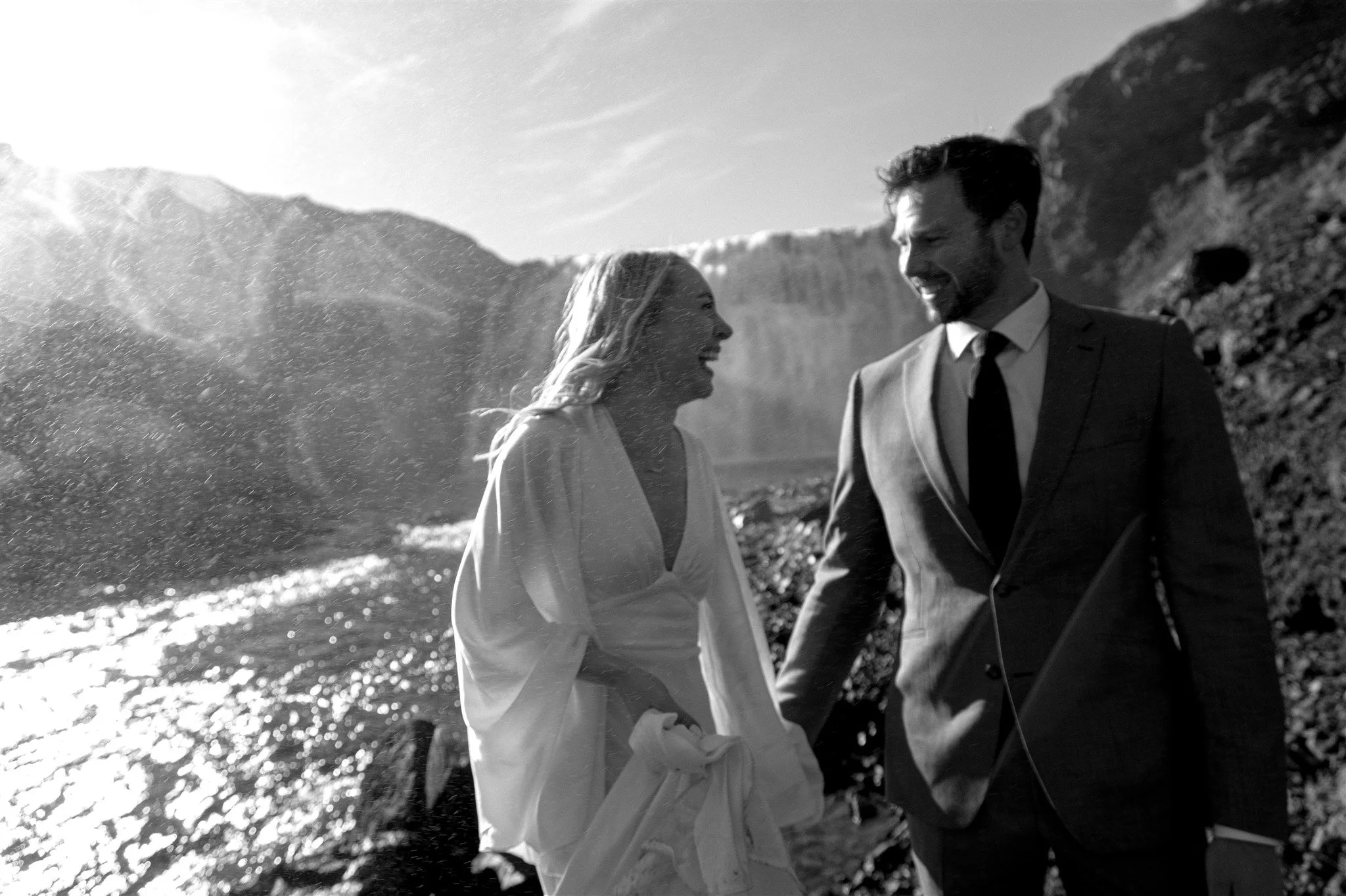 Lord of the Rings Inspired Iceland Engagement Photoshoot at waterfall — couple standing together with Arwen inspired dress with beautiful light and waterfall mist