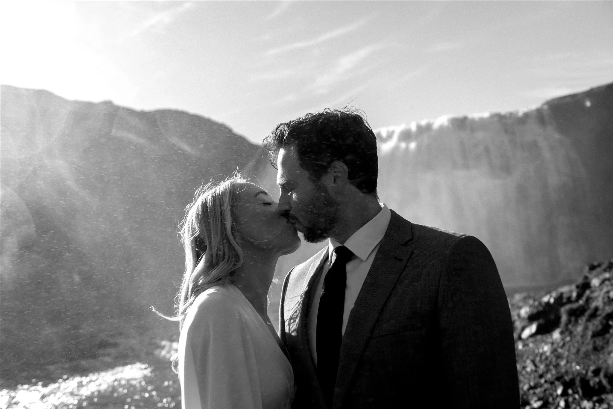 Lord of the Rings Inspired Iceland Engagement Photoshoot at waterfall — couple standing together with Arwen inspired dress with beautiful light and waterfall mist