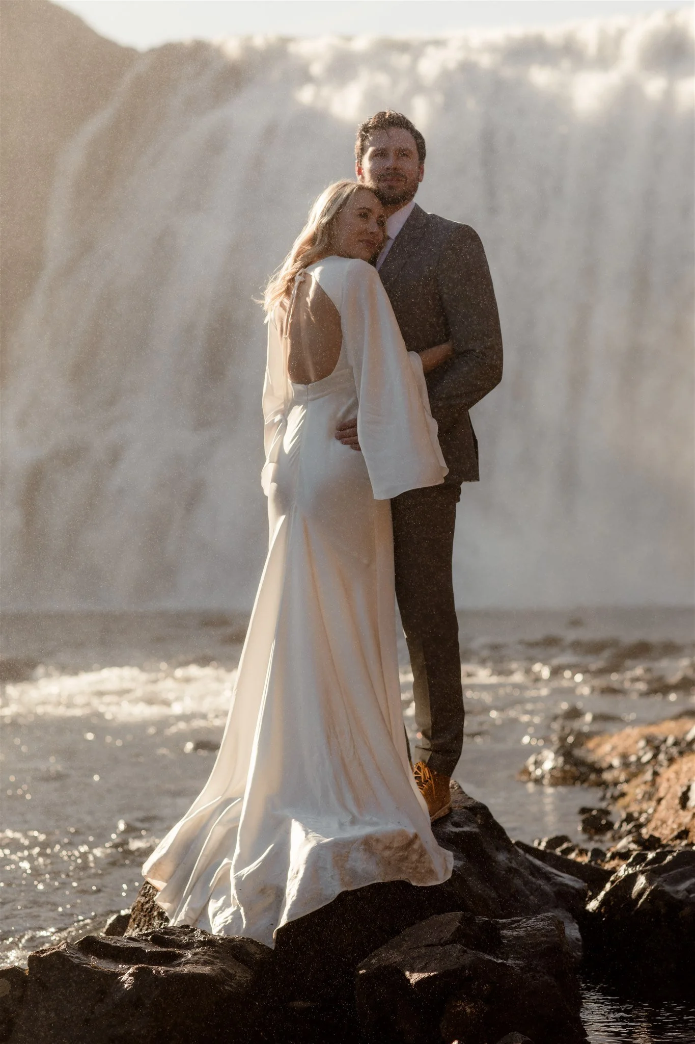 Lord of the Rings Inspired Iceland Engagement Photoshoot at waterfall — couple standing together with Arwen inspired dress with beautiful light and waterfall mist
