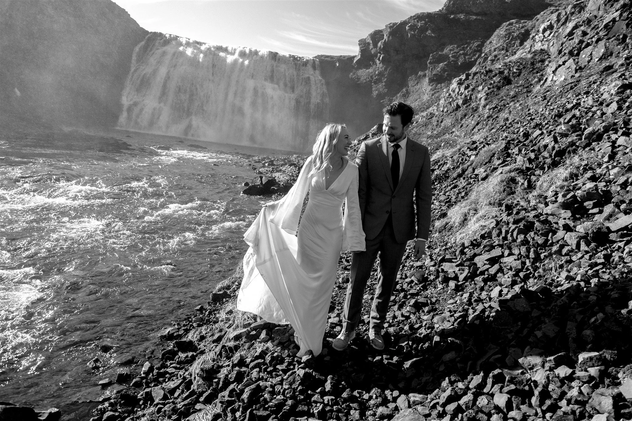 Lord of the Rings Inspired Iceland Engagement Photoshoot at waterfall — couple standing together with Arwen inspired dress with beautiful light and waterfall mist