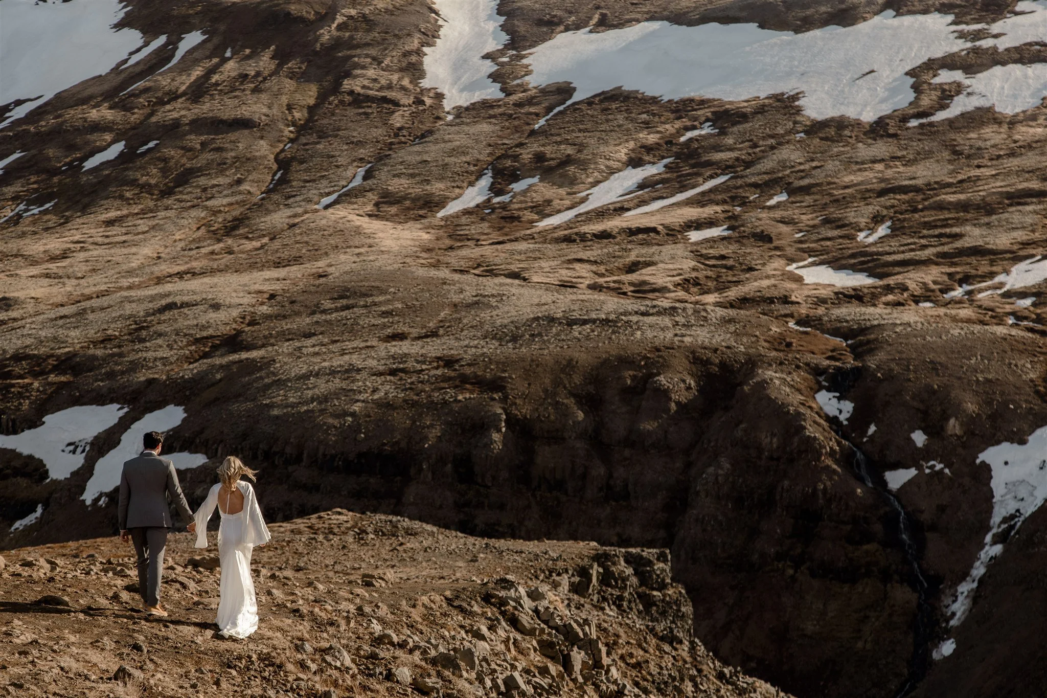 Lord of the Rings Inspired Iceland Engagement Photoshoot at waterfall — couple standing together with Arwen inspired dress with beautiful light and waterfall mist