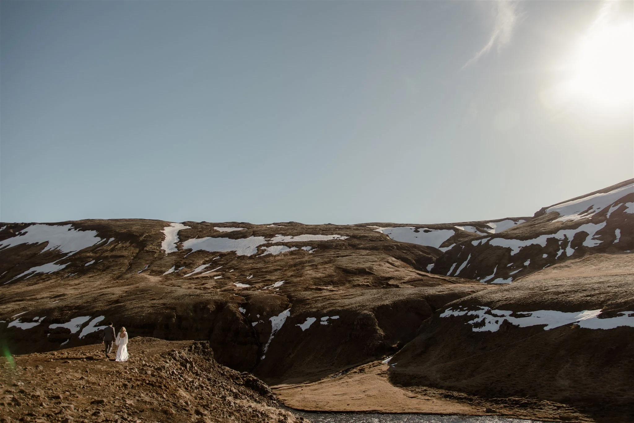 Lord of the Rings Inspired Iceland Engagement Photoshoot at waterfall — couple standing together on cliffs with Arwen inspired dress 