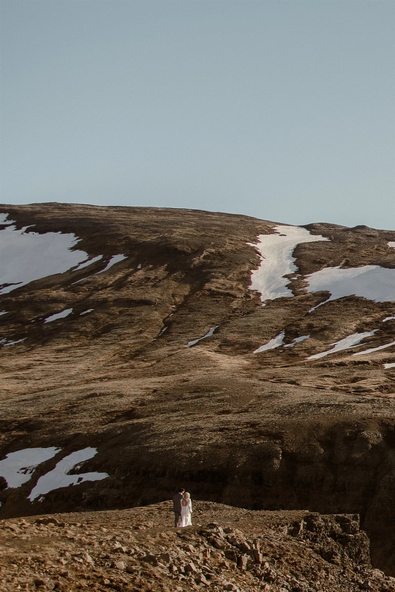 Lord of the Rings Inspired Iceland Engagement Photoshoot at waterfall — couple standing together on cliffs with Arwen inspired dress 