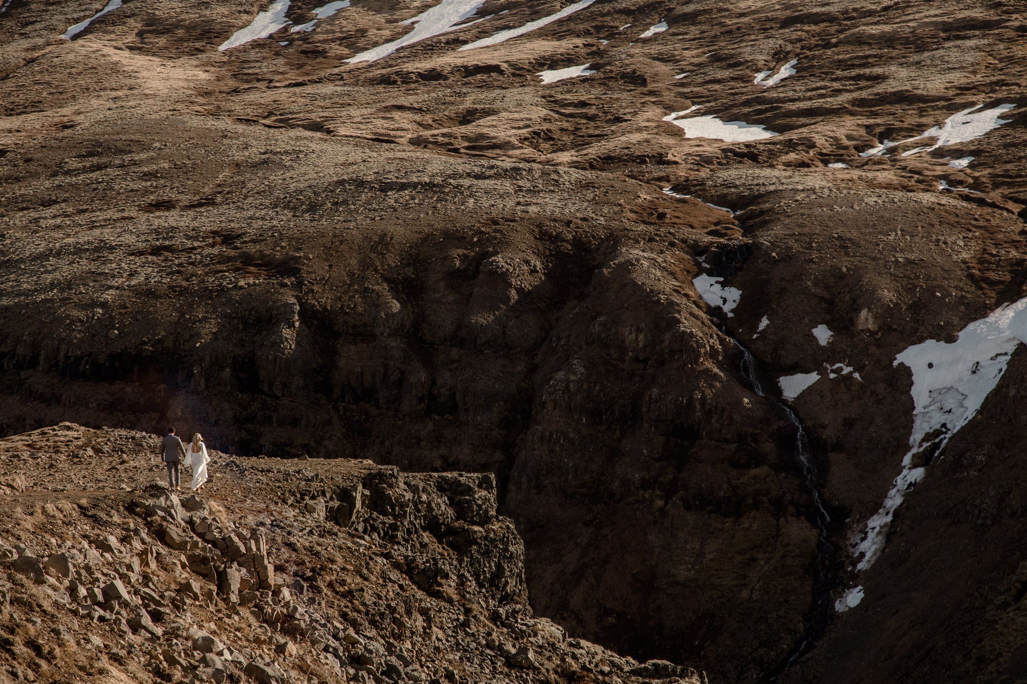 Lord of the Rings Inspired Iceland Engagement Photoshoot at waterfall — couple standing together on cliffs with Arwen inspired dress 