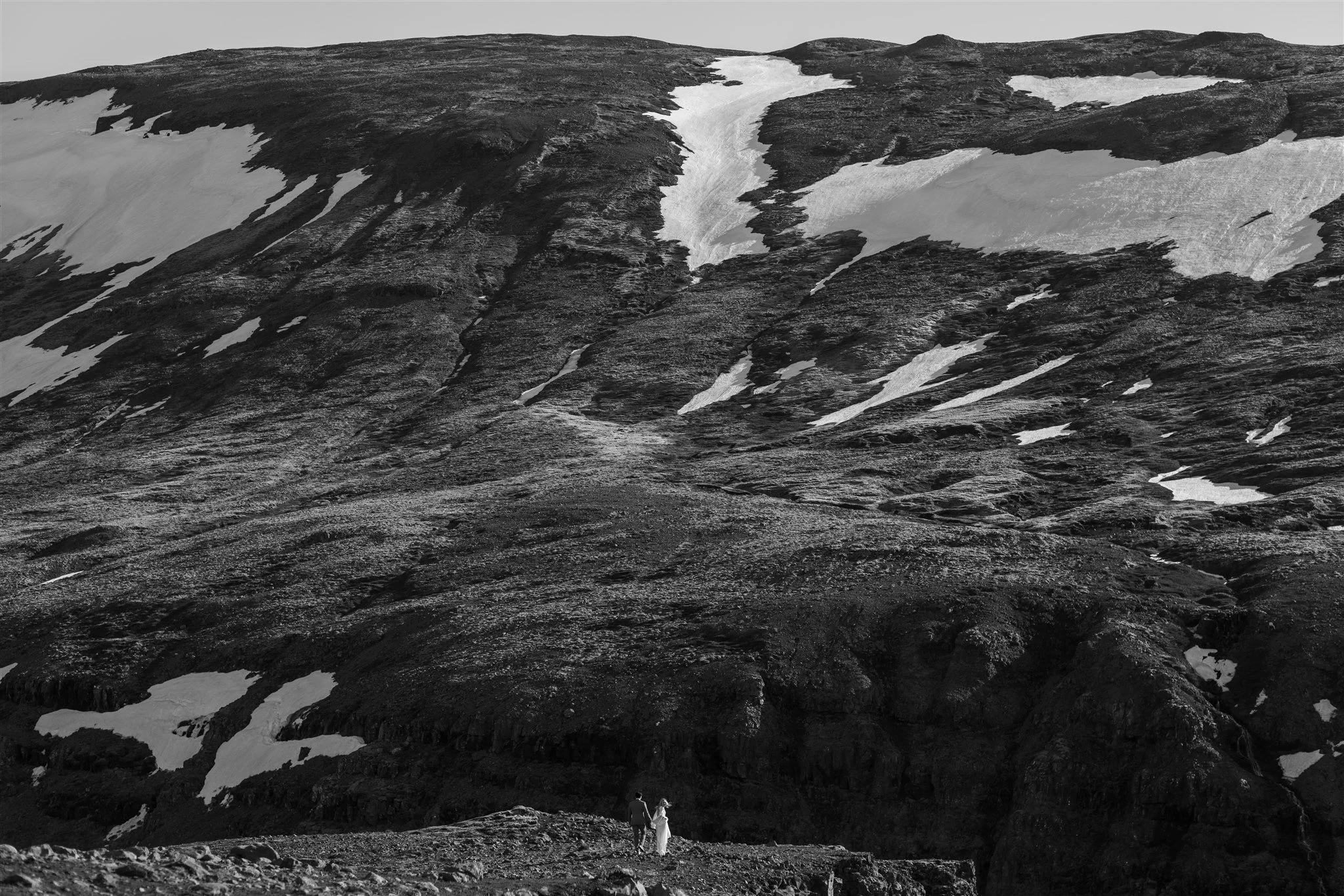 Lord of the Rings Inspired Iceland Engagement Photoshoot at waterfall — couple standing together on cliffs with Arwen inspired dress 
