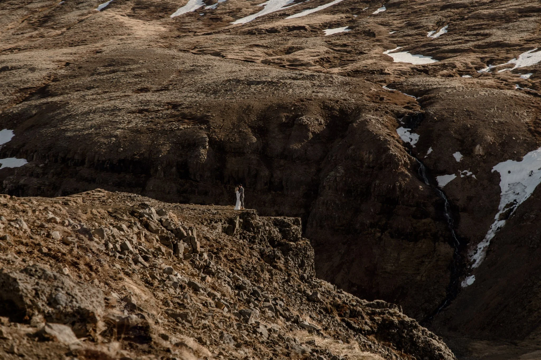 Lord of the Rings Inspired Iceland Engagement Photoshoot at waterfall — couple standing together on cliffs with Arwen inspired dress 