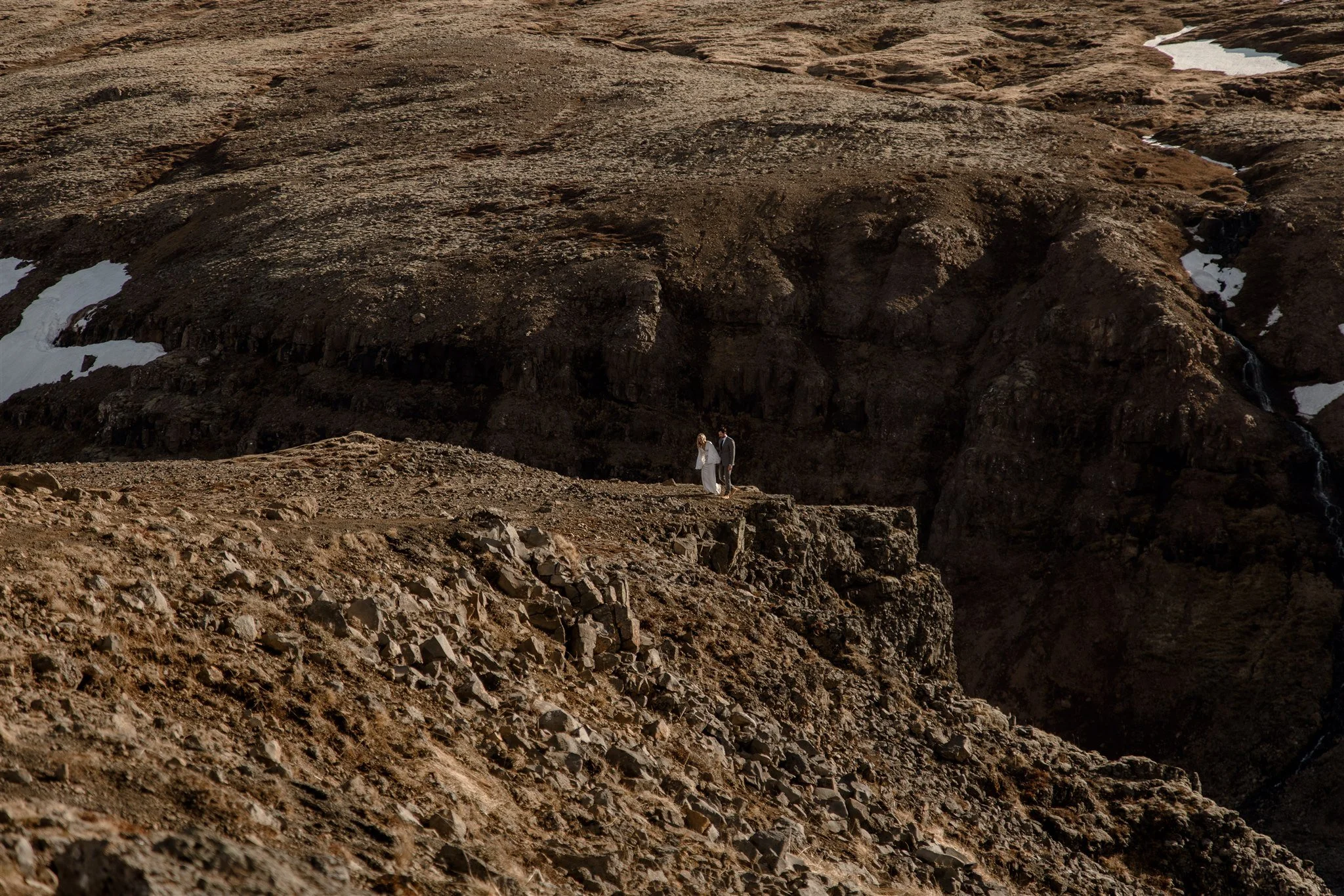 Lord of the Rings Inspired Iceland Engagement Photoshoot at waterfall — couple standing together on cliffs with Arwen inspired dress 