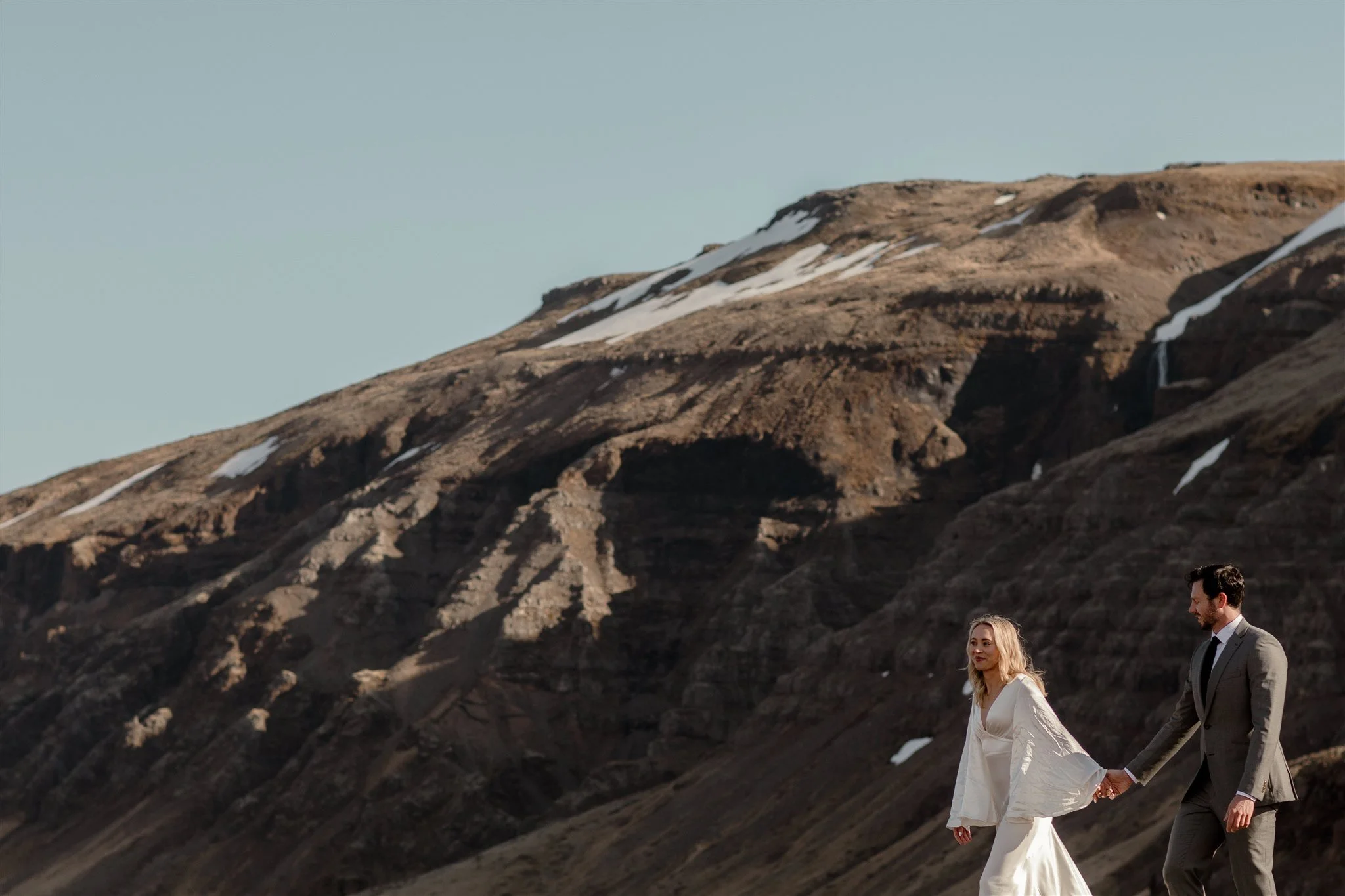Lord of the Rings Inspired Iceland Engagement Photoshoot at waterfall — couple walking together with Arwen inspired dress 