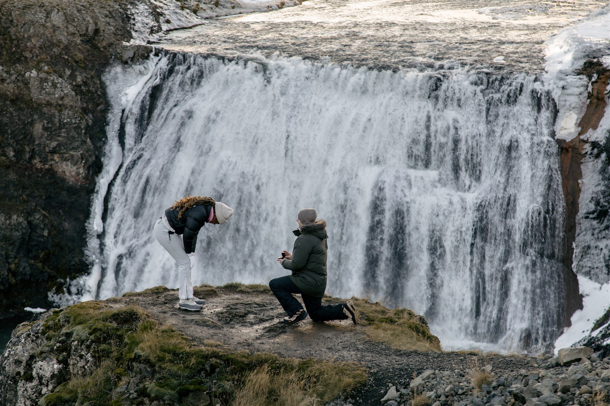 Iceland proposal at a secluded waterfall in the winter with the female partner so excited in disbeleif
