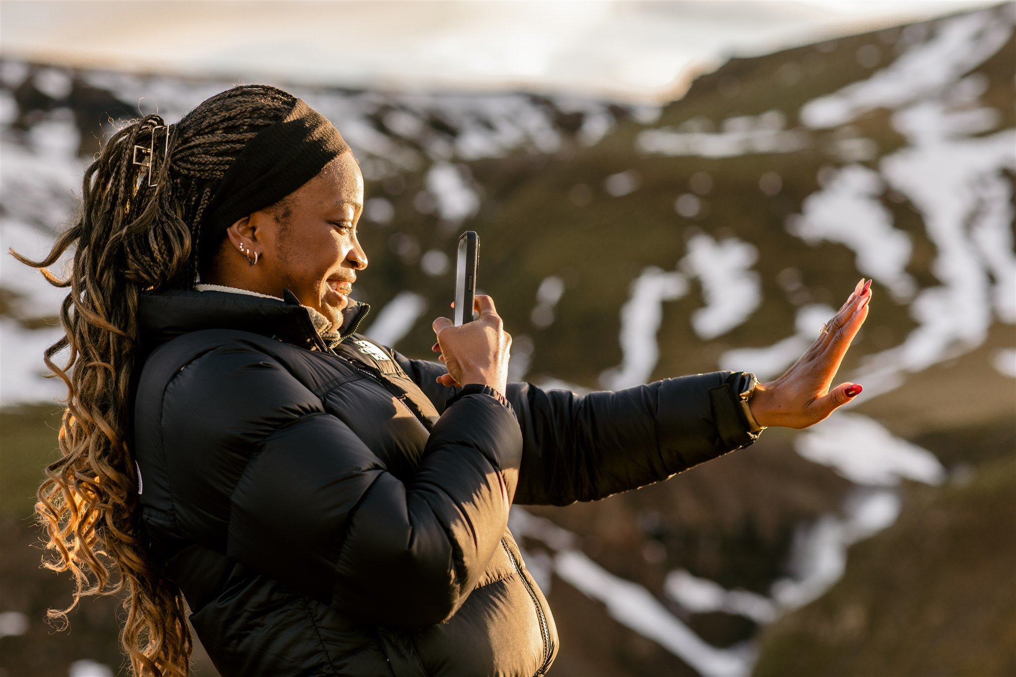 the newly engaged woman is taking a photo of her new engagement ring to show her family after her surprise and secret Iceland proposal.