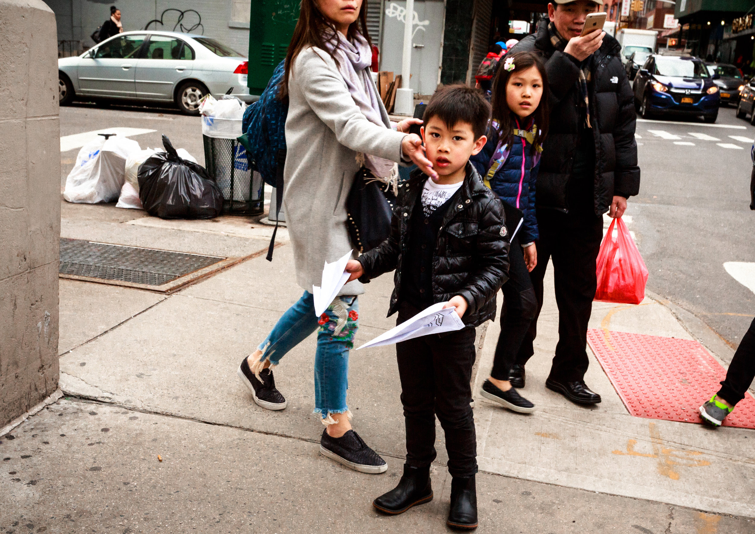 Chinese_Boy_With_Paper_Airplanes_Proteected_by_Mother_Chinatown_NYC_2017.jpg