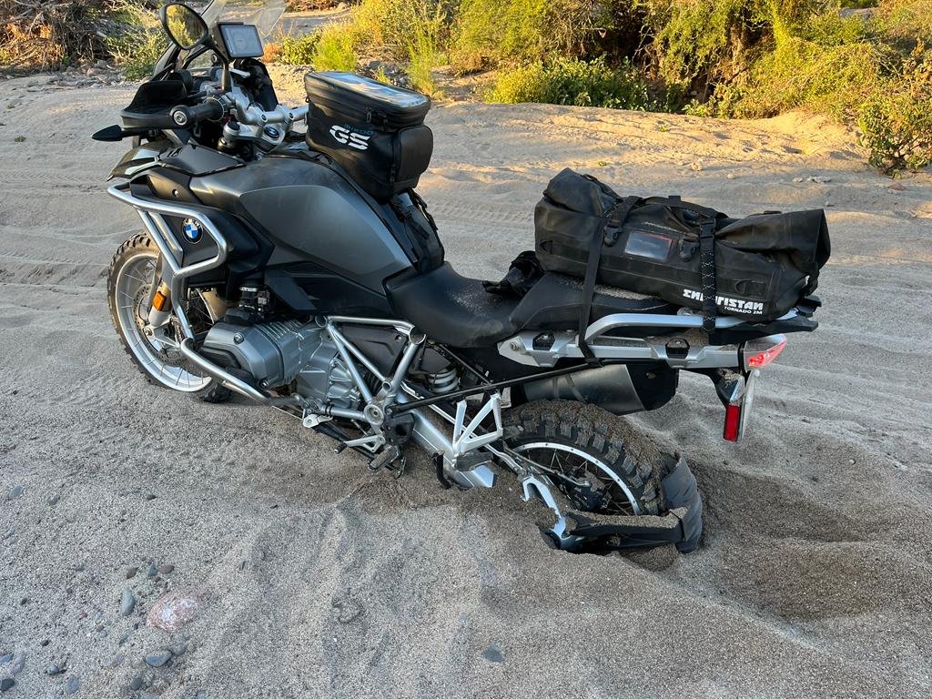 Black motorcycle stuck in sand