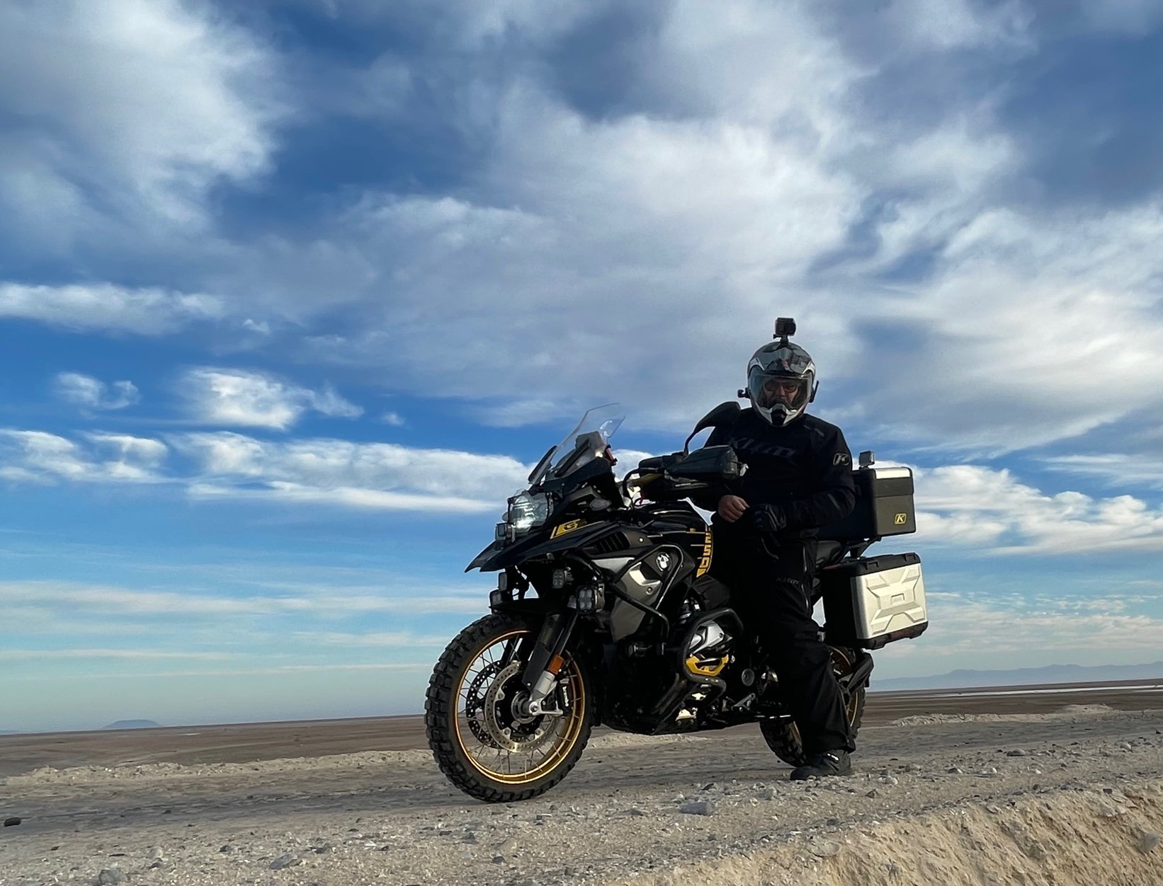 Motorcycle stopped in desert with blue sky and clouds in background