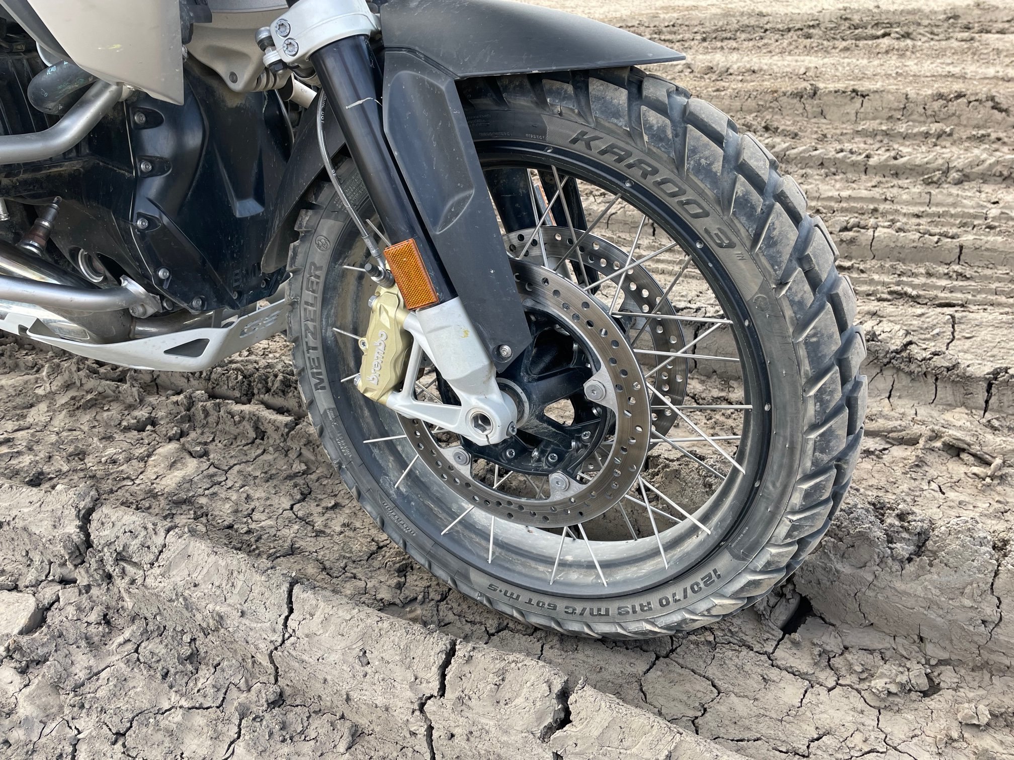 Motorcycle wheel in deep dried mud ruts.