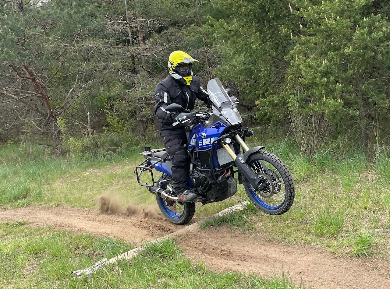  Motorcycle doing a wheelie over a log on a trail.   