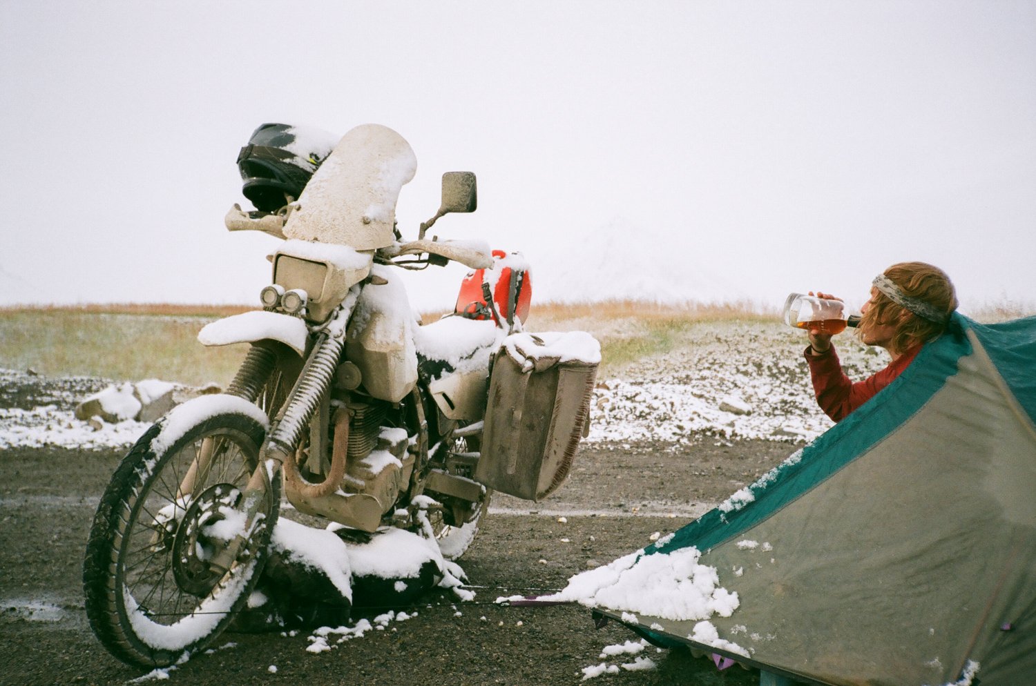  Motorcycle, rider and tent set up in a snowy camping site. 