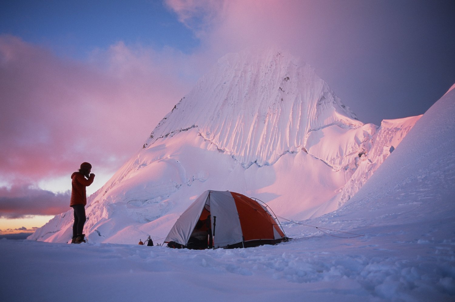  Man and tent camped in snow on mountain. 