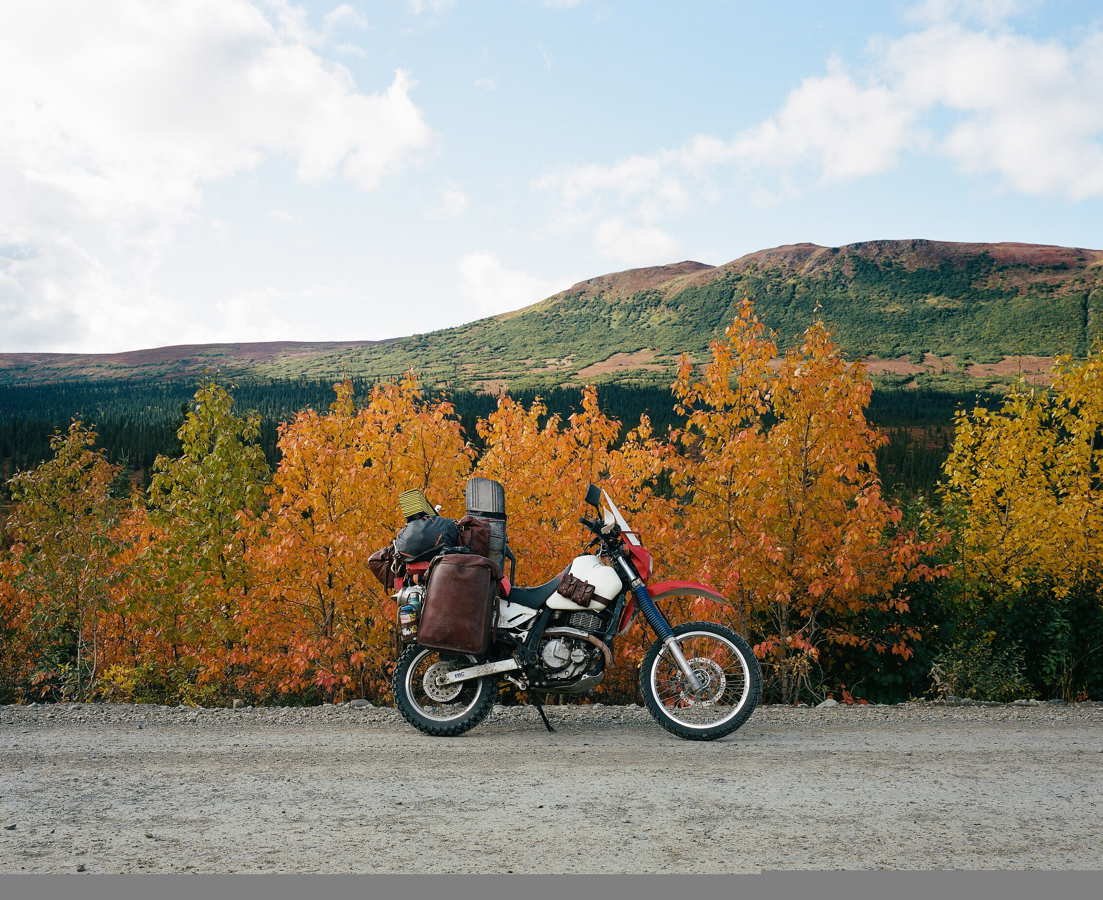  Motorcycle at side of the highway on an autumn day with mountains in background. 