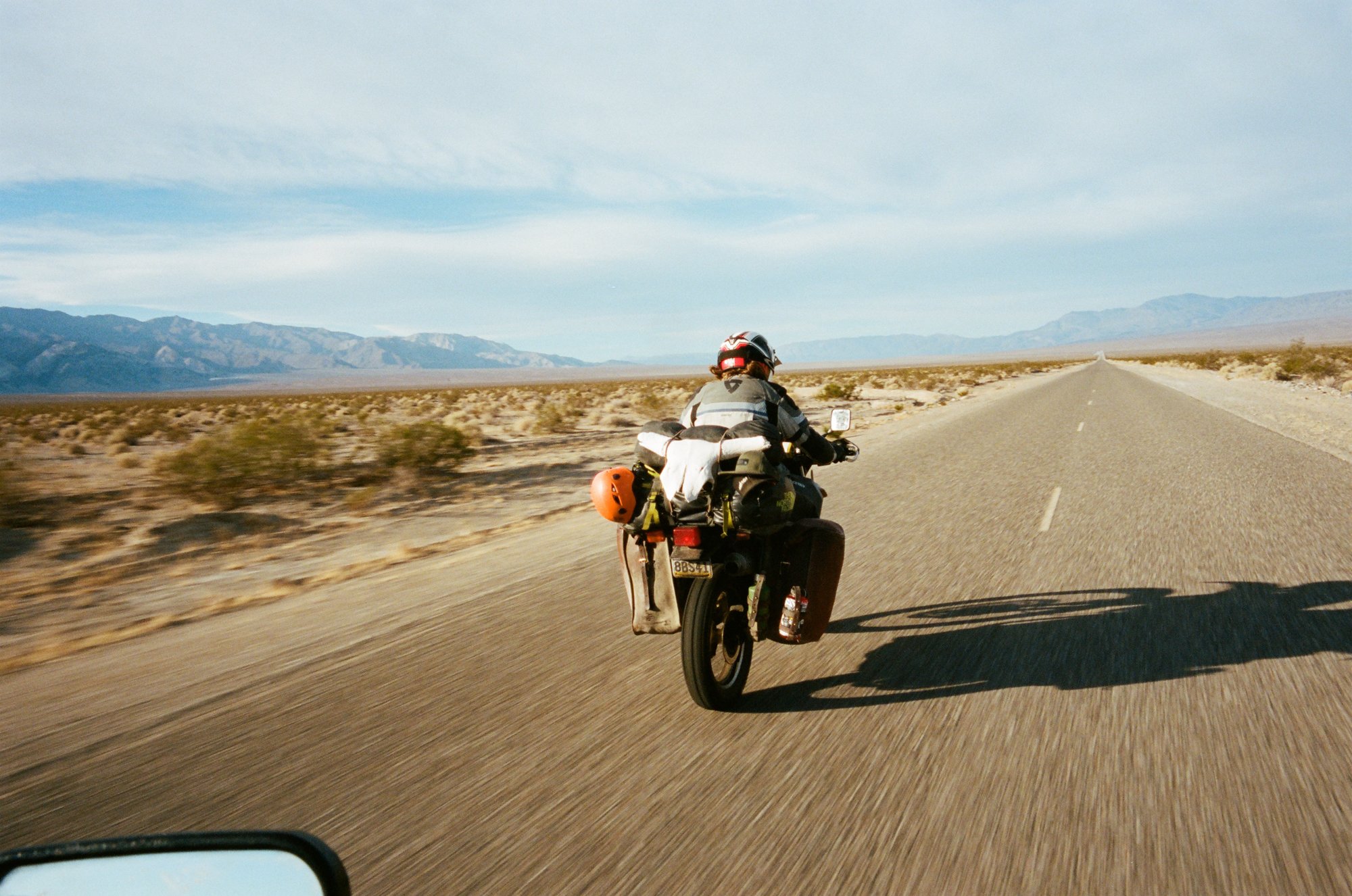  Motorcycle riding on road with mountains in the background. 