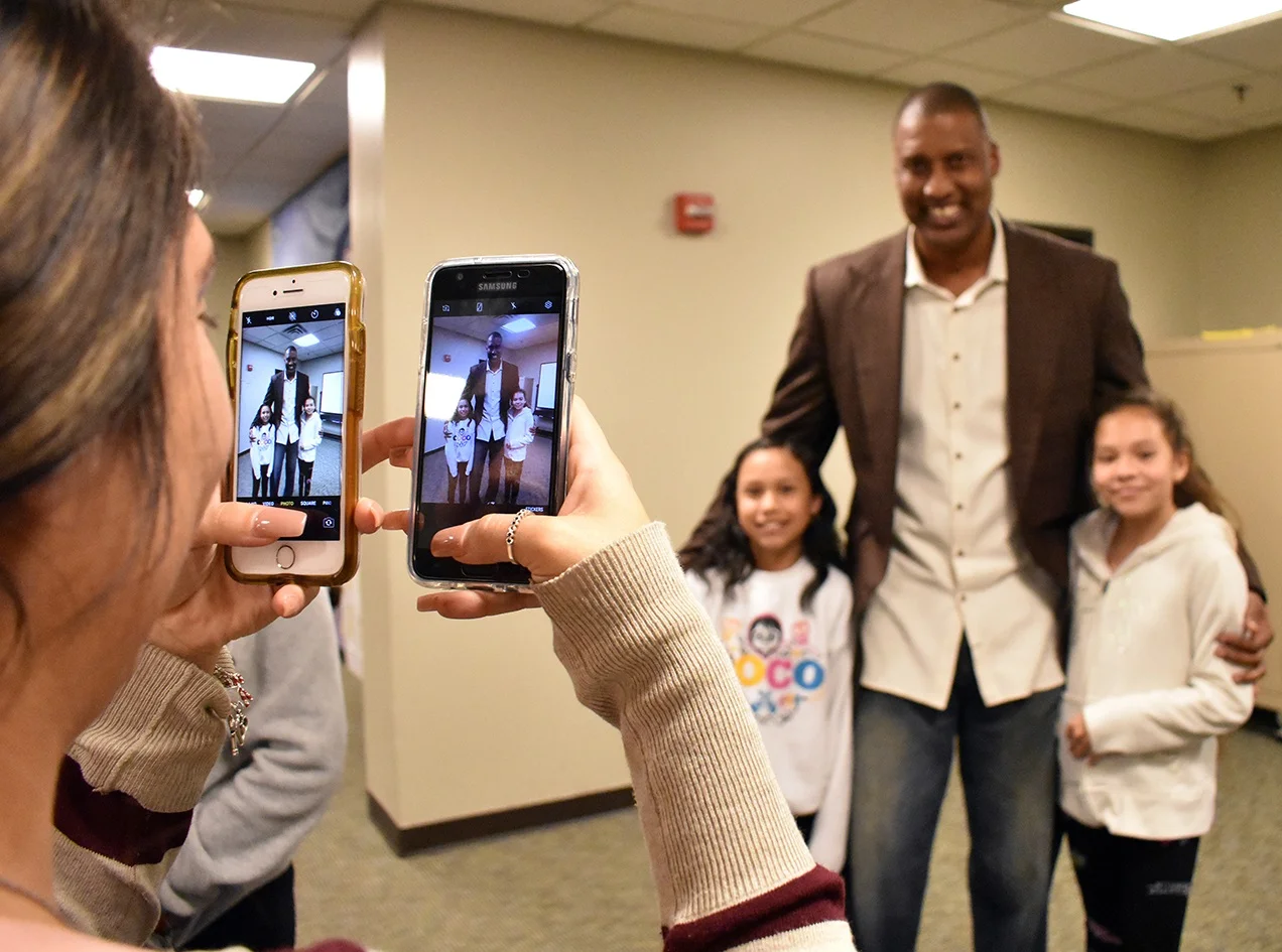 Former pro-basketball player Derrick Battie poses for a photo with two kids from Junior Crew.