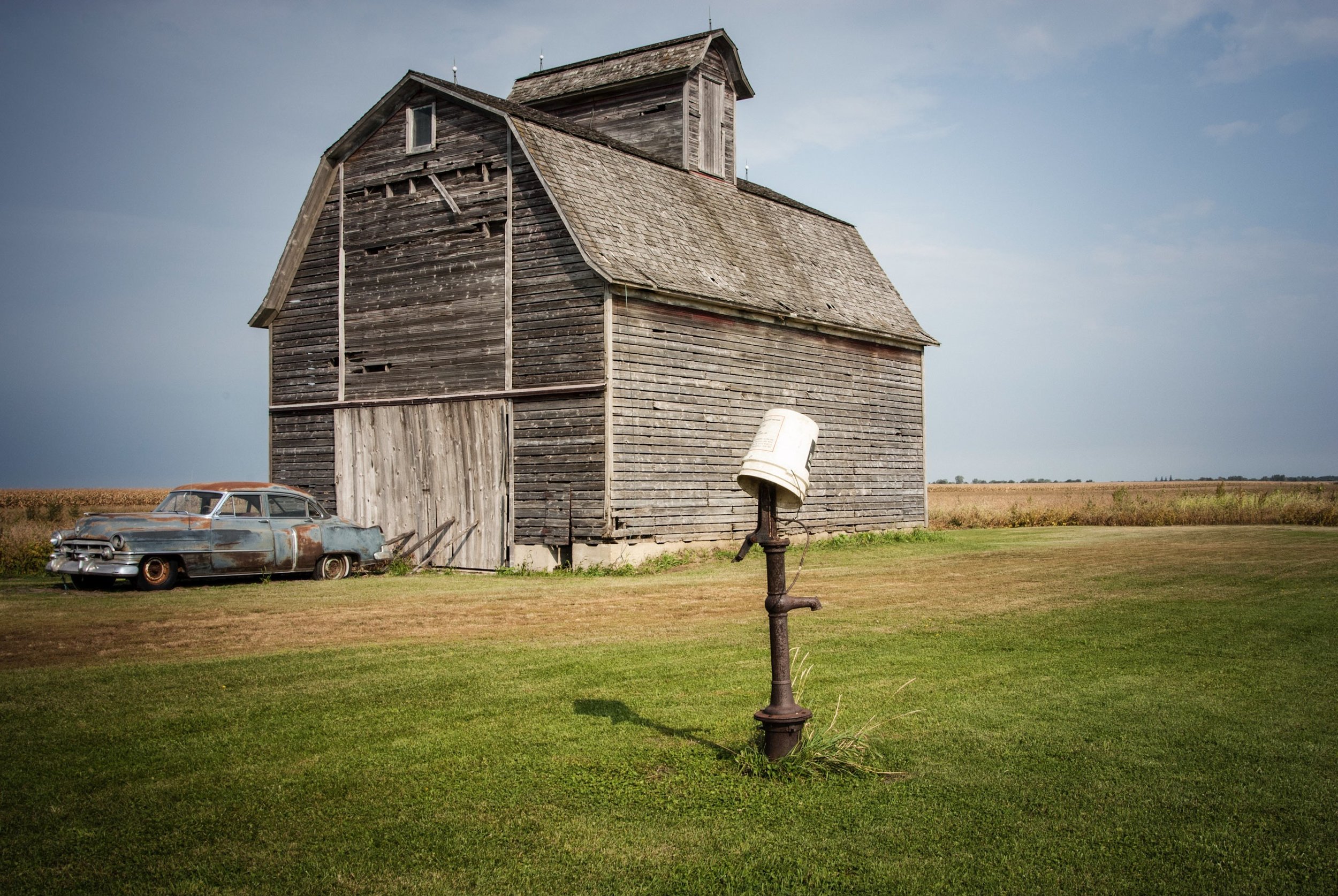 Time passes by. Do we remember where we are? Do we recognize the place? What lies within that barn? Why has the car been left there? Why is this cancer still within us? (Photographed in Rural Illinois)