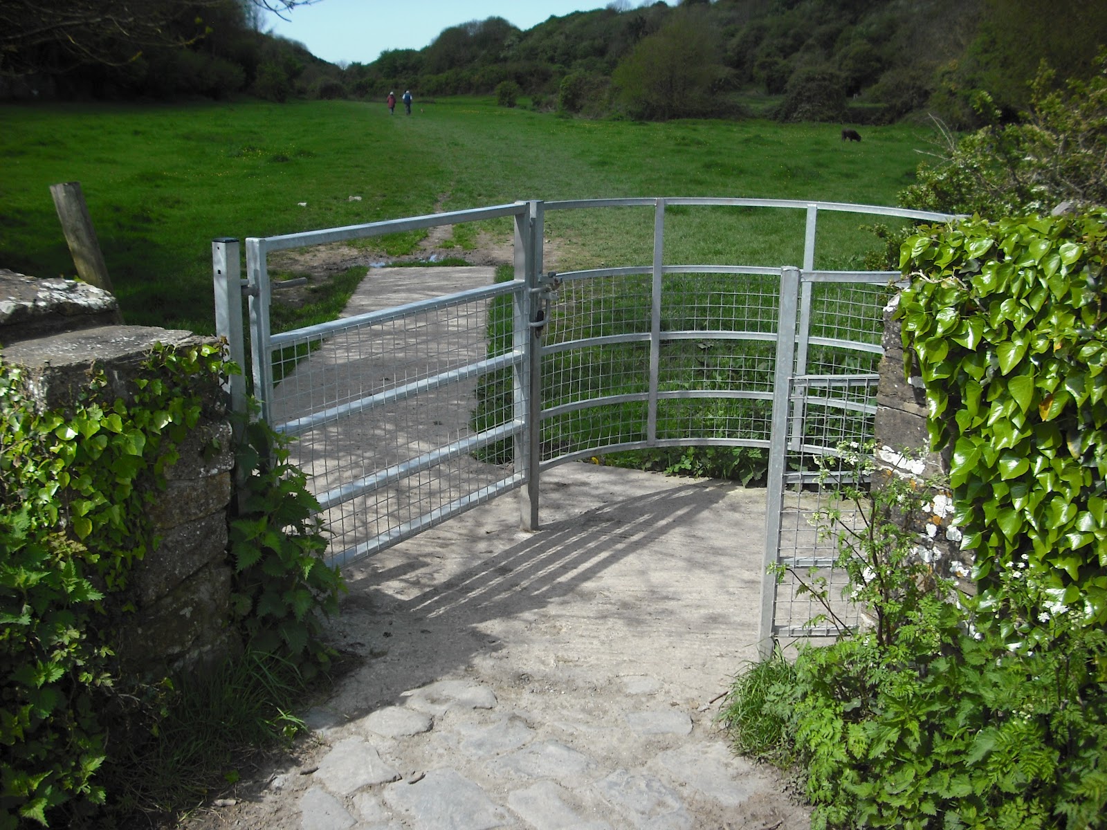 This elegant galvanized pipe stile is paved, and defends the ground against foot traffic and erosion. This type of stile is known as a "kissing gate".