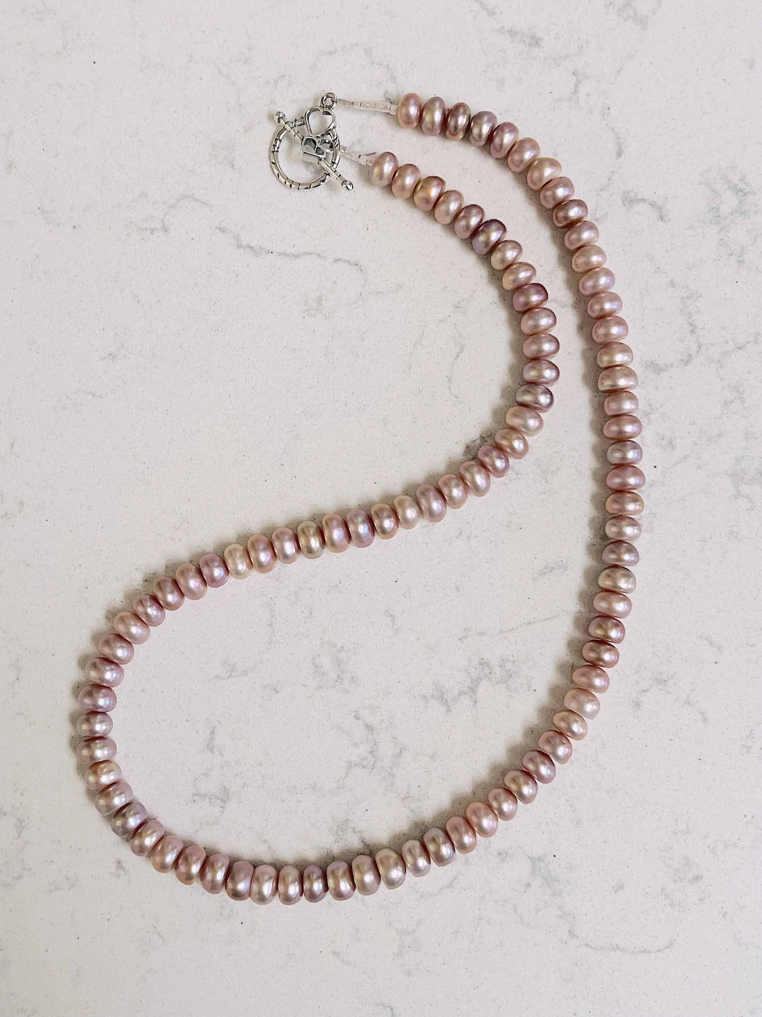 Mauve button pearls curved on quartz.jpg