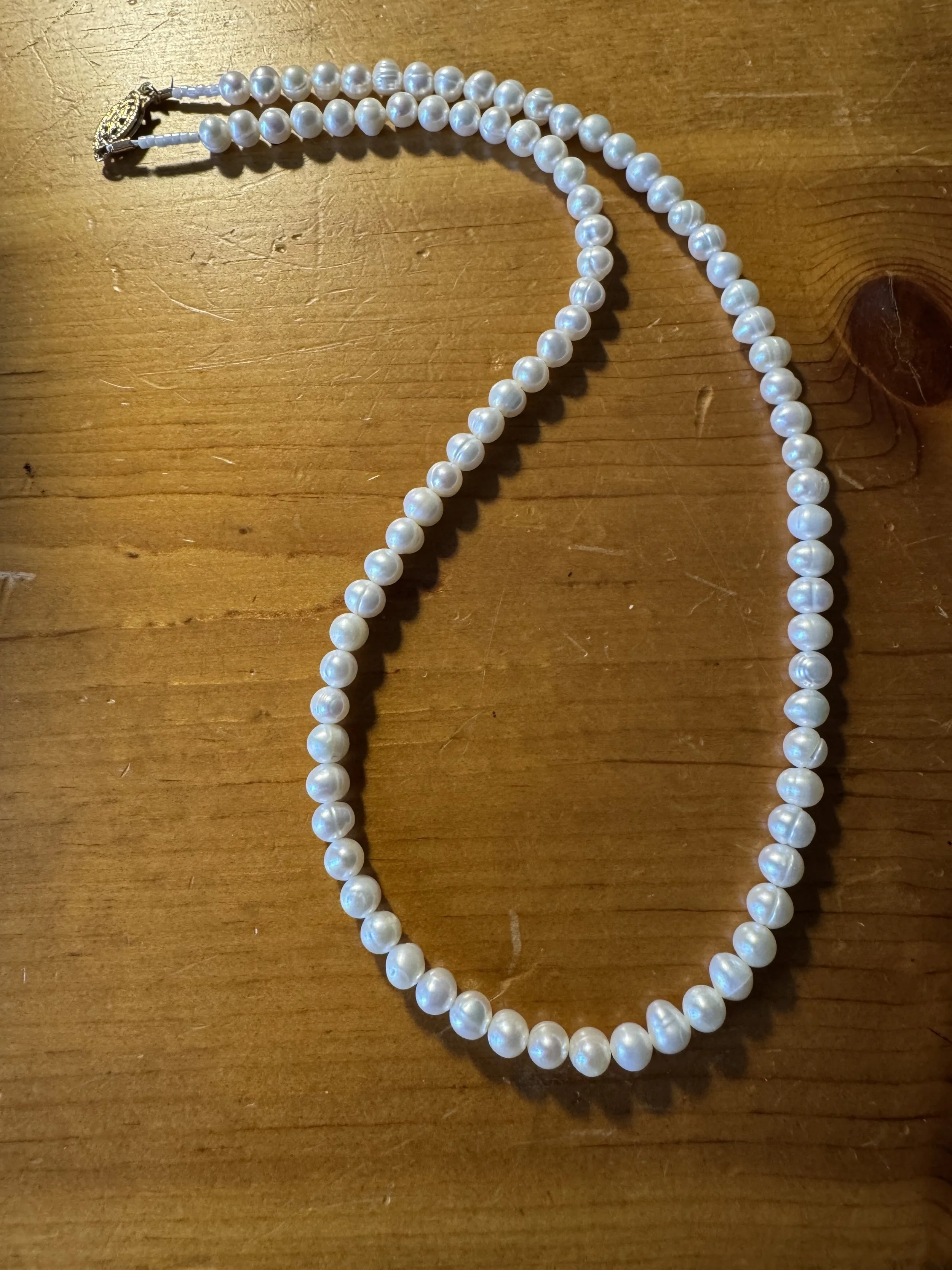 Cultured white pearls with gold clasp curved.jpg