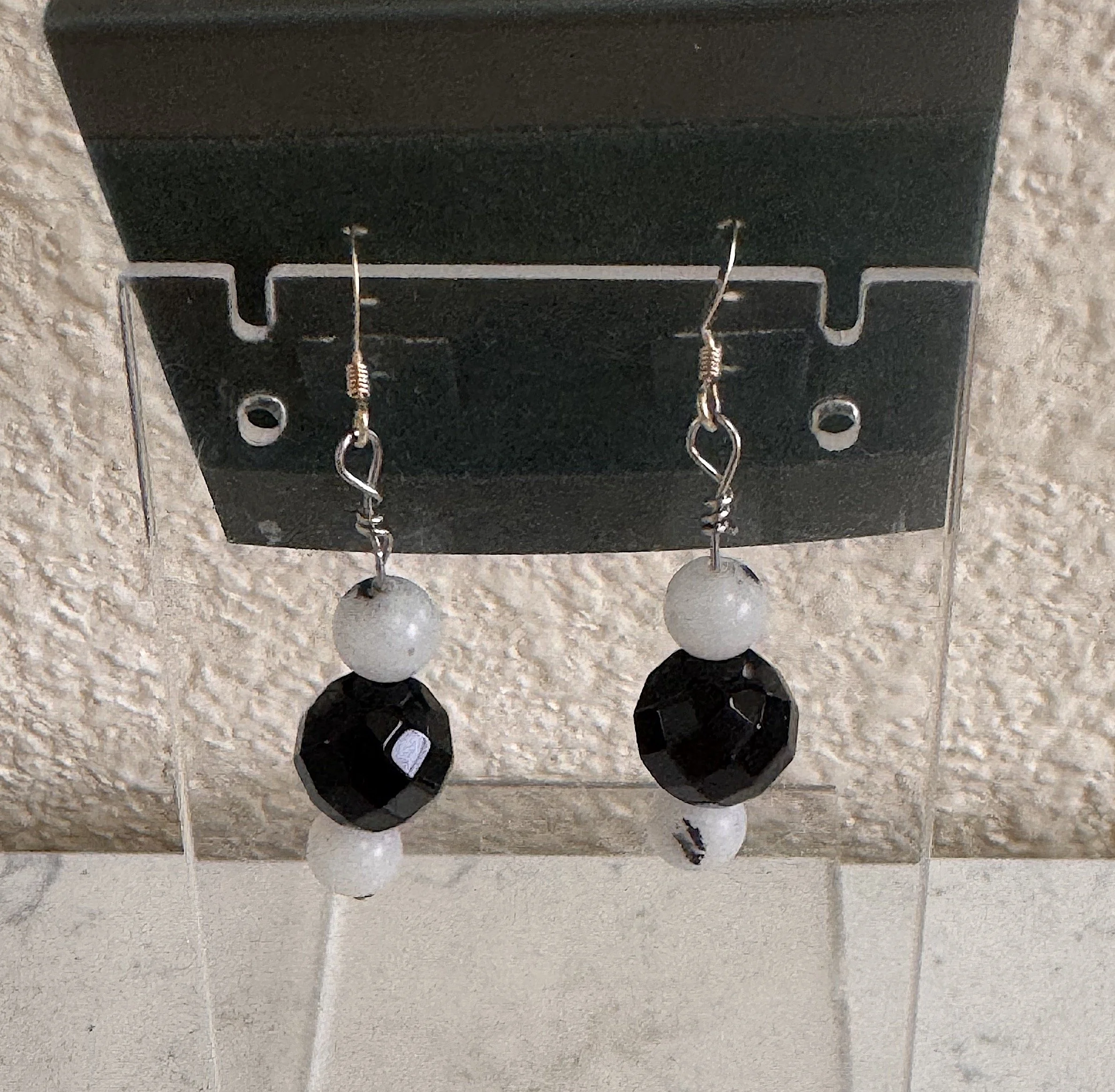 Onyx and Tourmalinated Quartz earrings on stand.jpeg