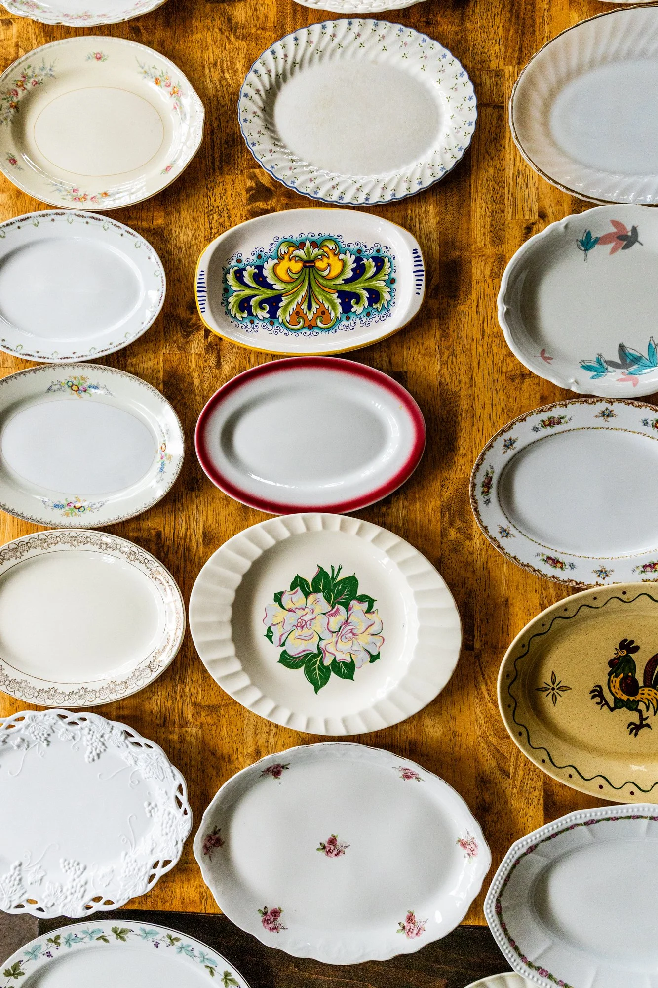 A collection of various decorative and patterned ceramic and porcelain plates and dishes laid out on a wooden surface. Southbound Food Festival in Birmingham, Alabama.