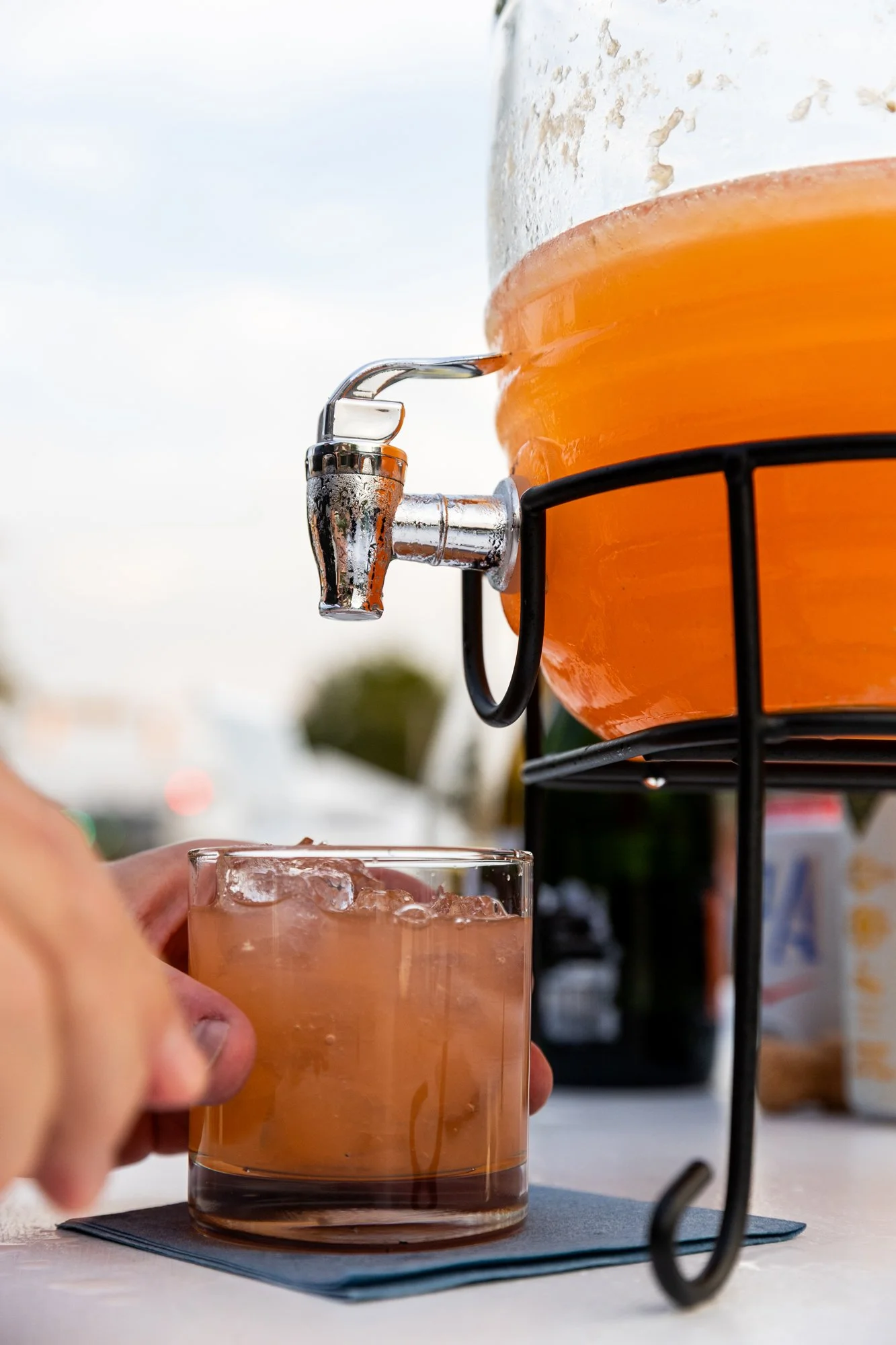 A glass being filled with pink lemonade from a beverage dispenser outdoors. Southbound Food Festival in Birmingham, Alabama.