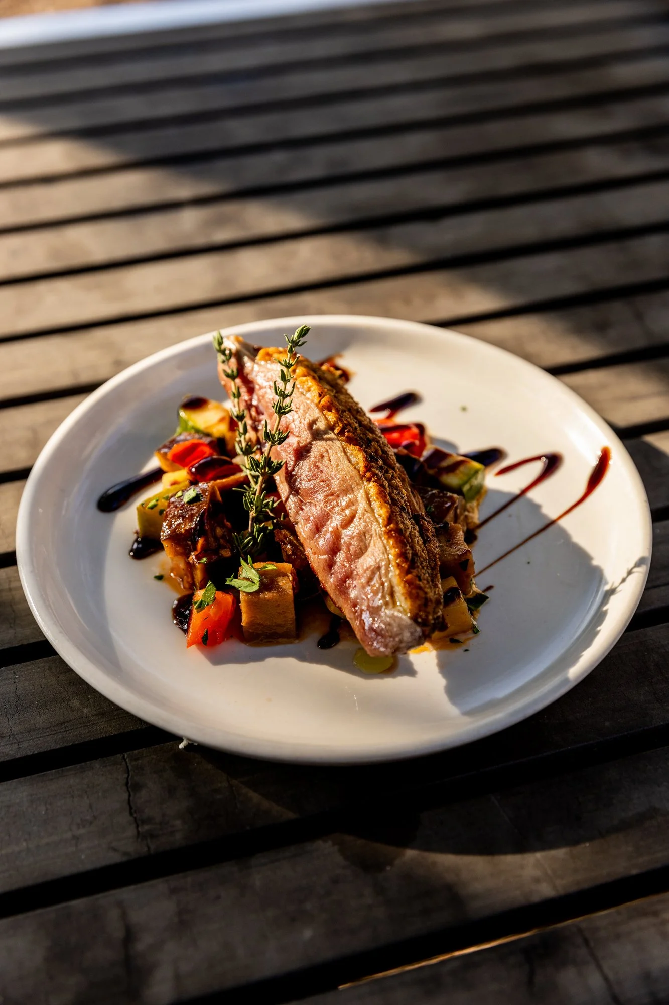 Grilled fish fillet served over vegetables with a garnish of herbs and drizzled with sauce. Ovenbird Restaurant in Birmingham, Alabama.