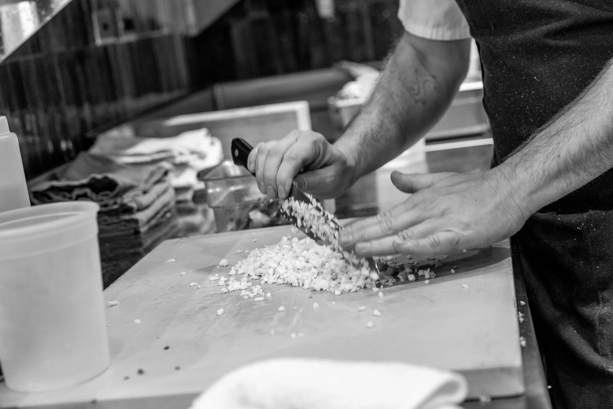 Person chopping ingredients on a cutting board in a kitchen.
