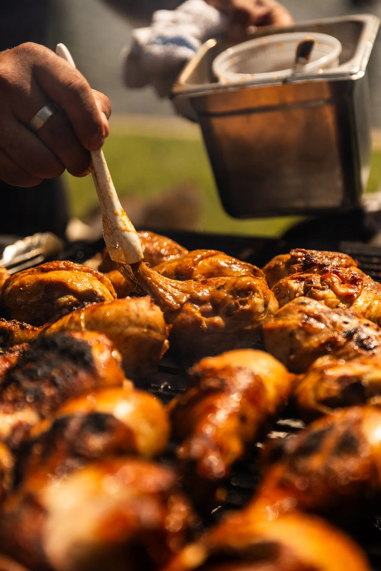 Close-up of a person using tongs to cook grilled chicken drumsticks on an outdoor grill. Southbound Food Festival in Birmingham, Alabama.