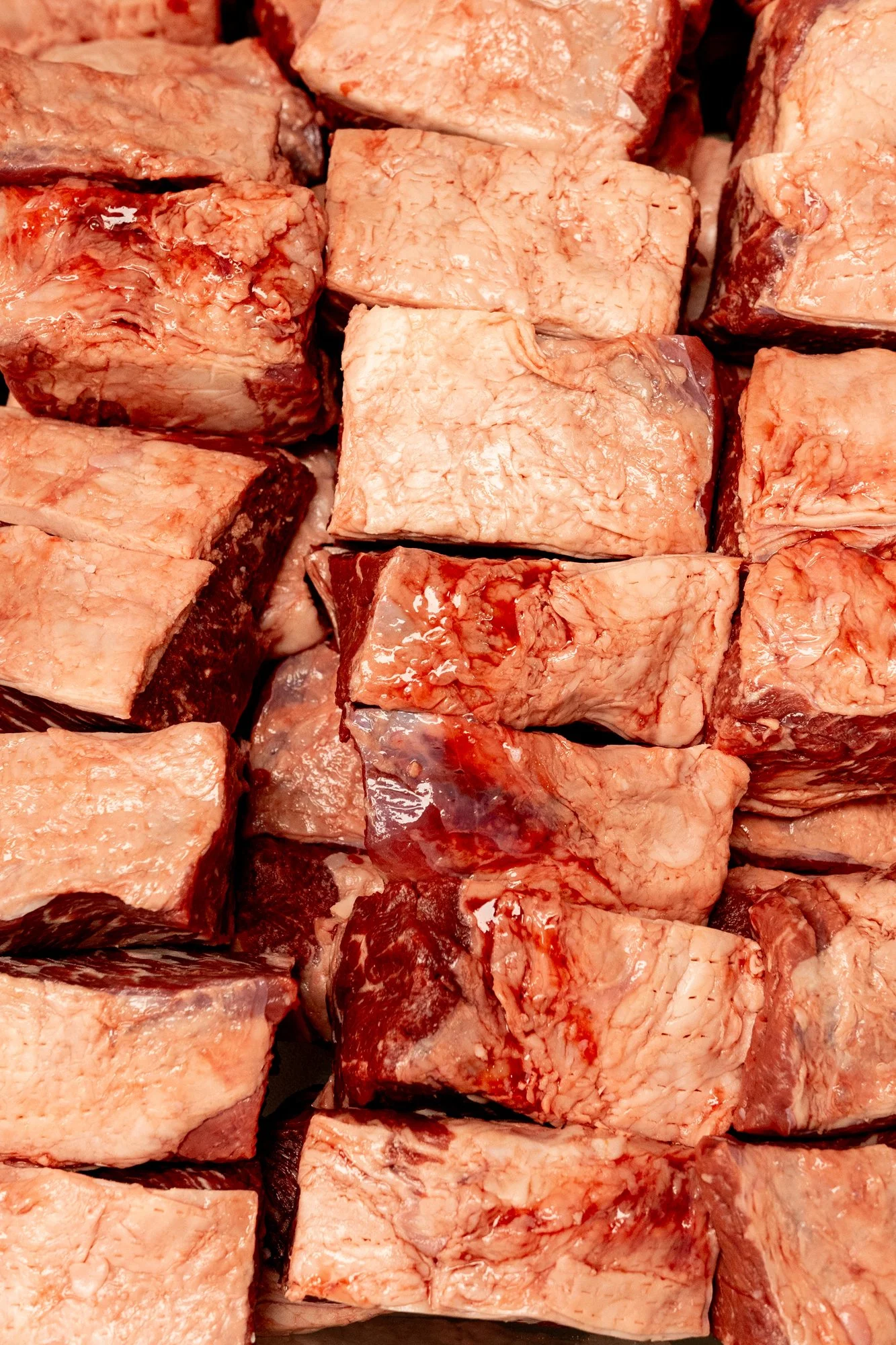 Close-up image of raw beef short ribs stacked together.