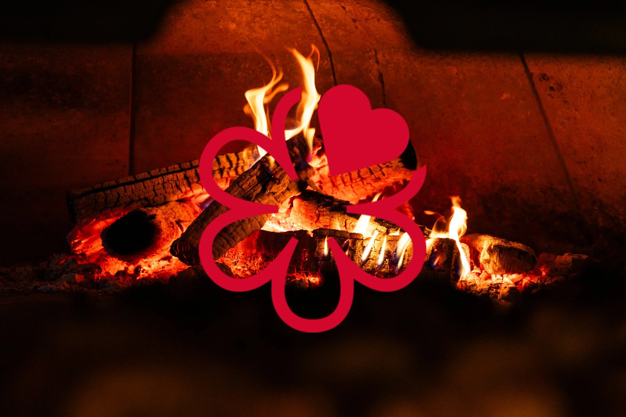 A fireplace with burning logs and flames, overlaid with a red outline drawing of a four-leaf clover and a heart.