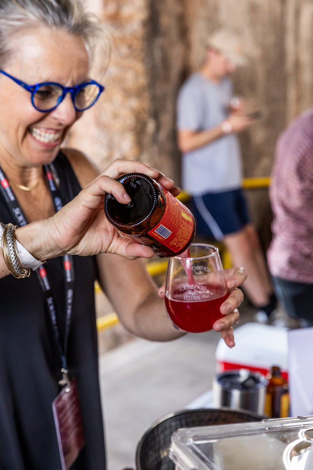 Woman pouring a red beverage from a bottle into a glass during a festival. Southbound Food Festival in Birmingham, Alabama.