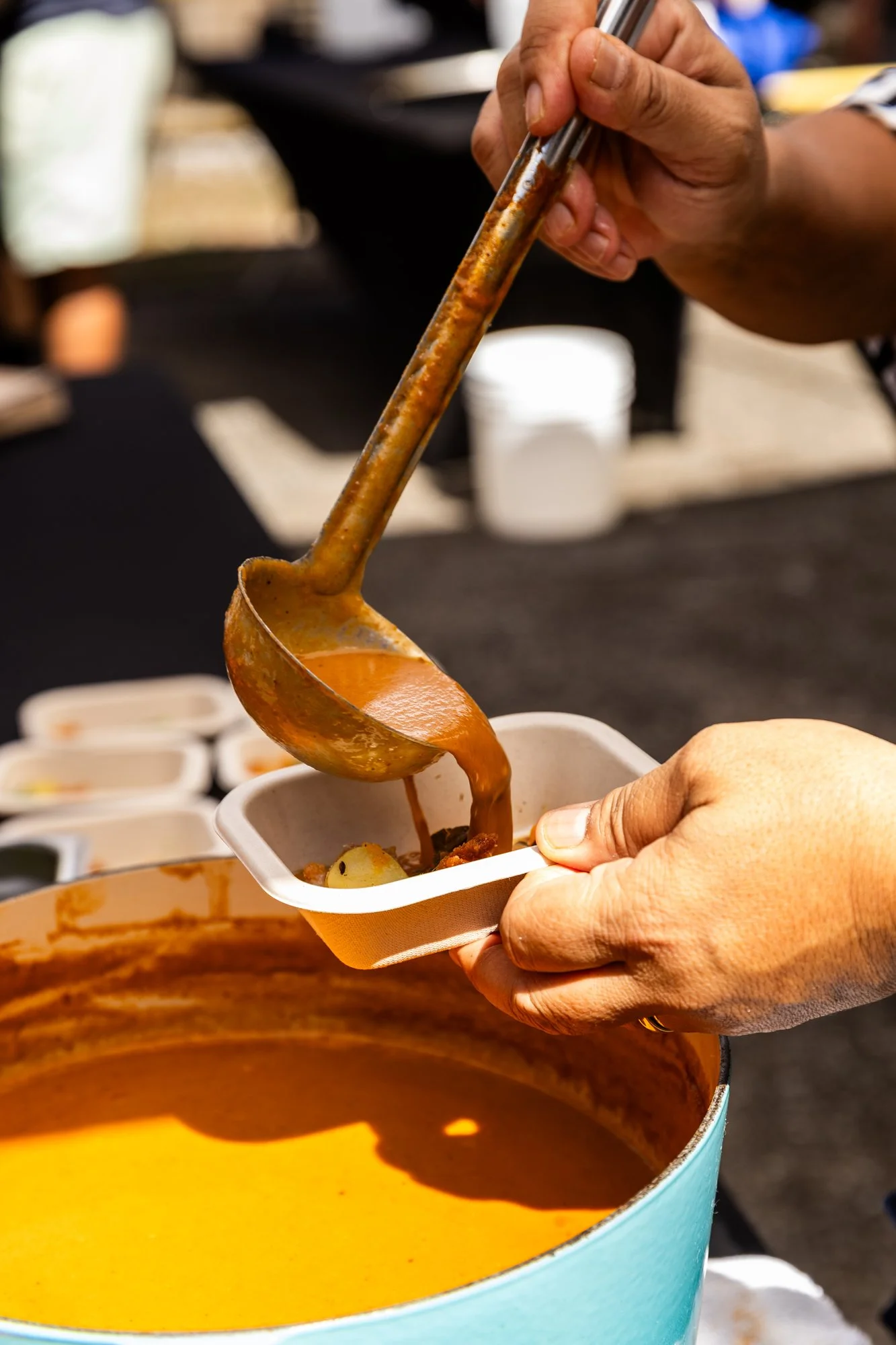 Person serving a bowl of hearty soup from a large pot with a ladle. Southbound Food Festival in Birmingham, Alabama.