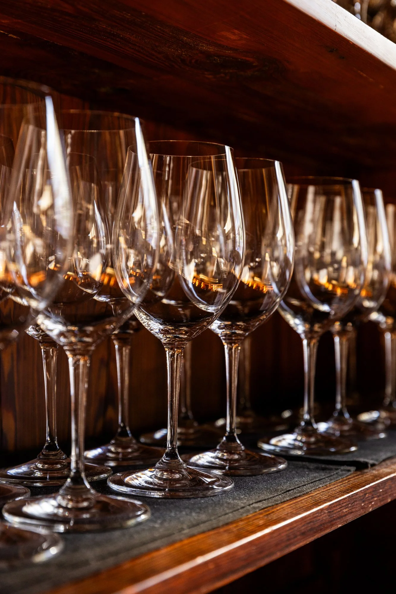 Multiple empty wine glasses on a wooden shelf. Hot and Hot Fish Club Restaurant in Birmingham, Alabama.