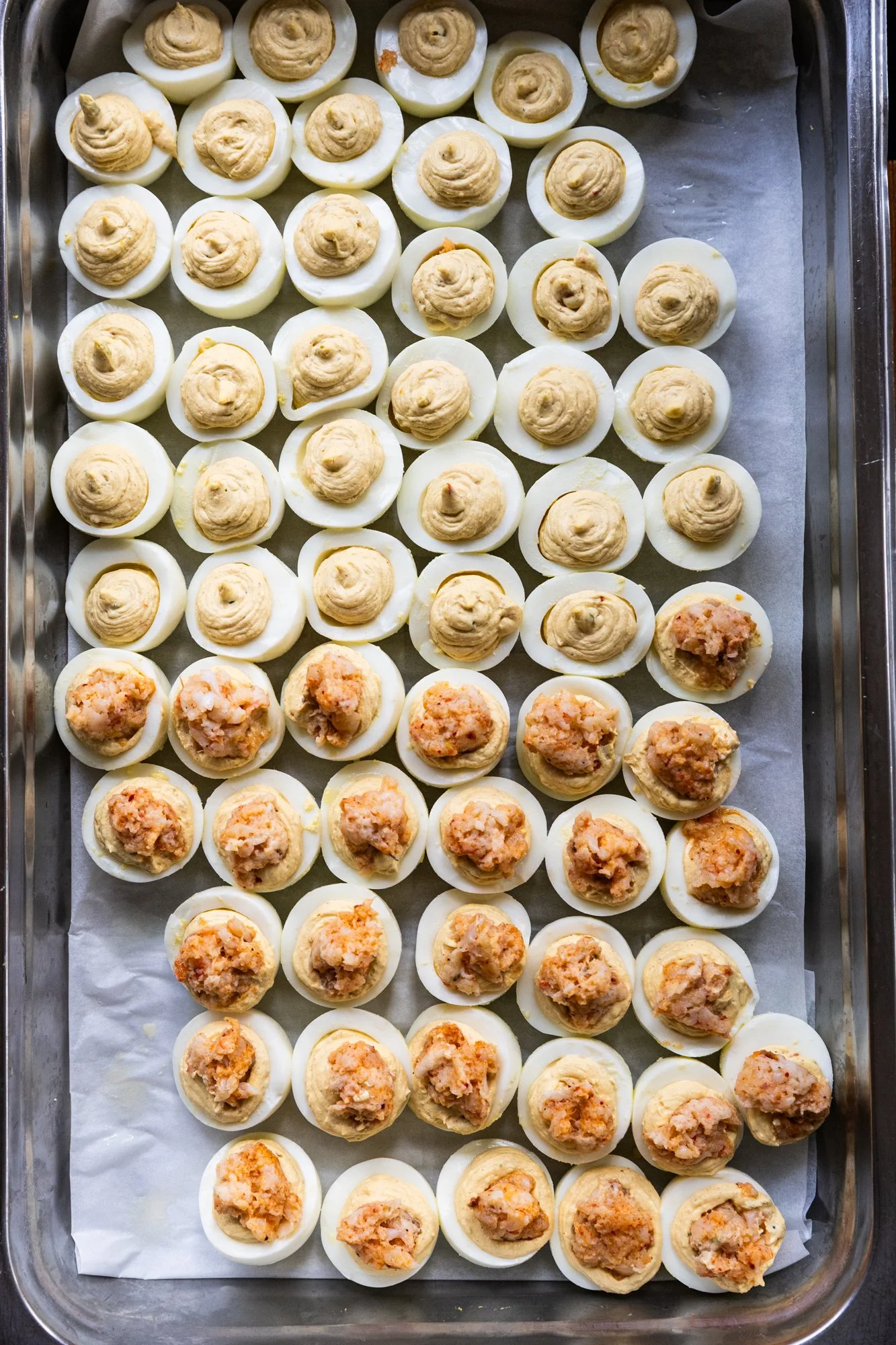 Tray of halved hard-boiled eggs filled with different types of stuffing or filling, arranged in rows on parchment paper. Southbound Food Festival in Birmingham, Alabama.