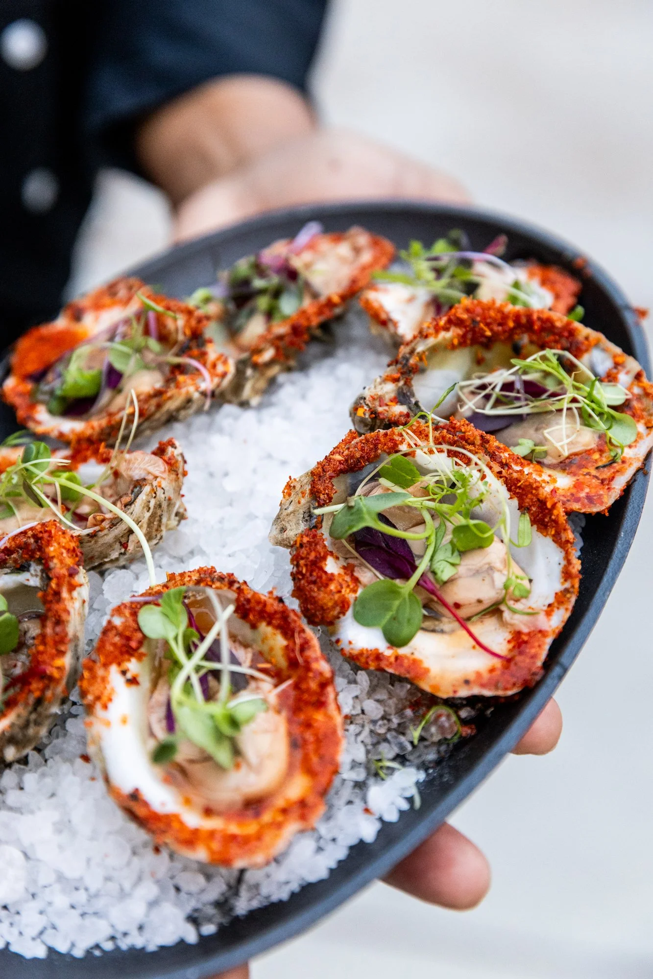 A black platter with ice, holding several pieces of seafood topped with microgreens and sauces. Southbound Food Festival in Birmingham, Alabama.
